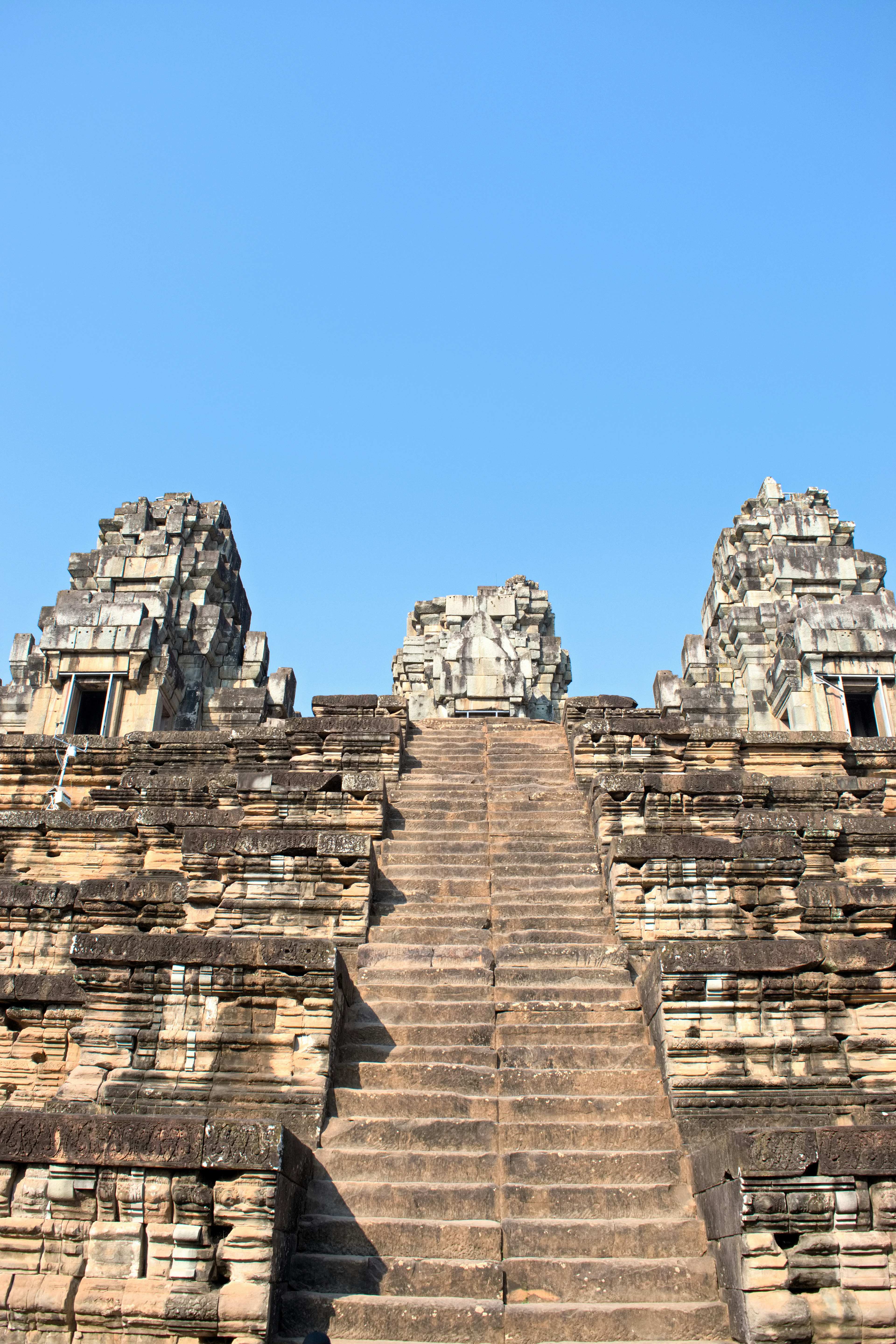 Tangga kuil menuju menara batu di bawah langit biru yang cerah