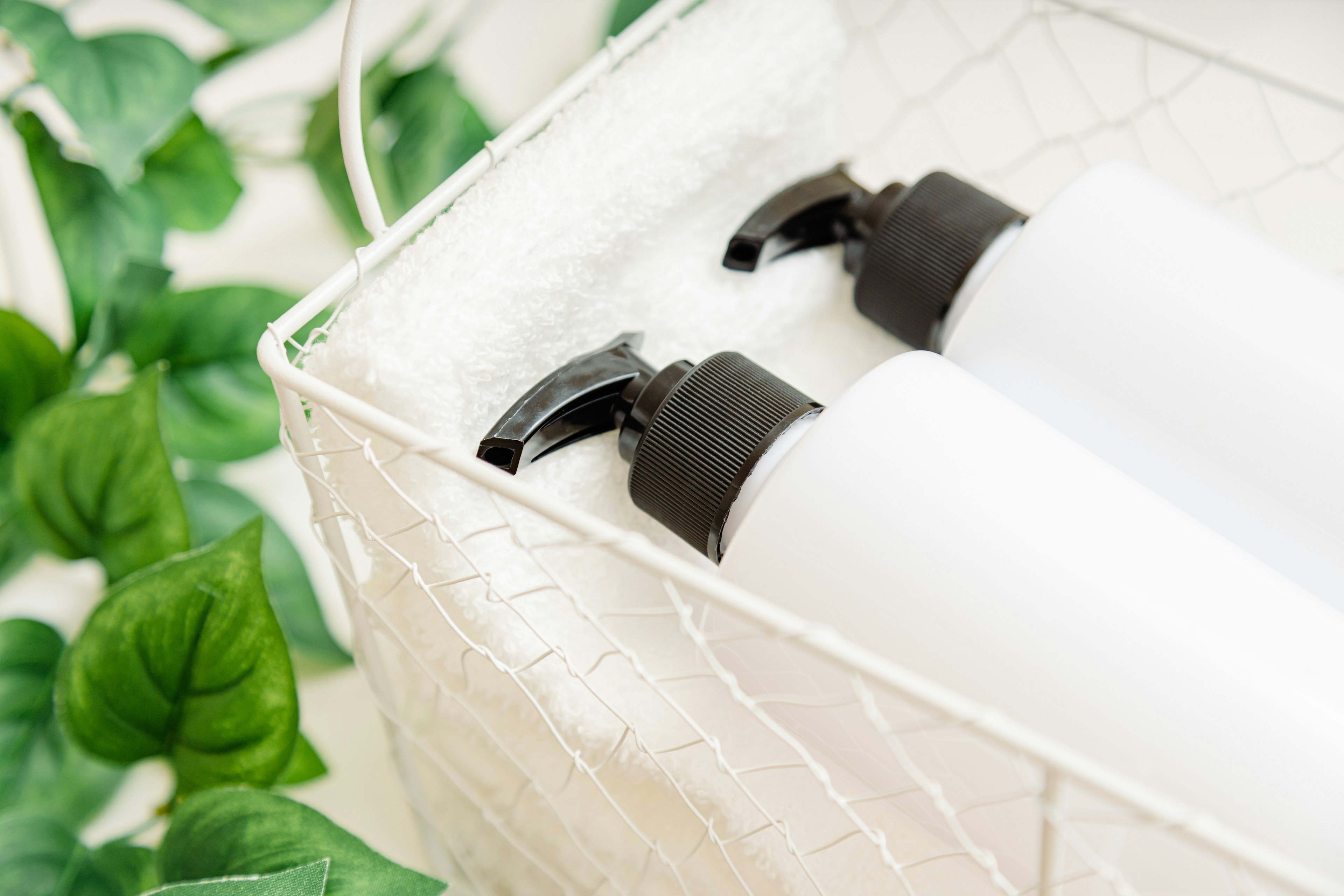 Scène avec des bouteilles à pompe blanches et des plantes vertes dans un panier