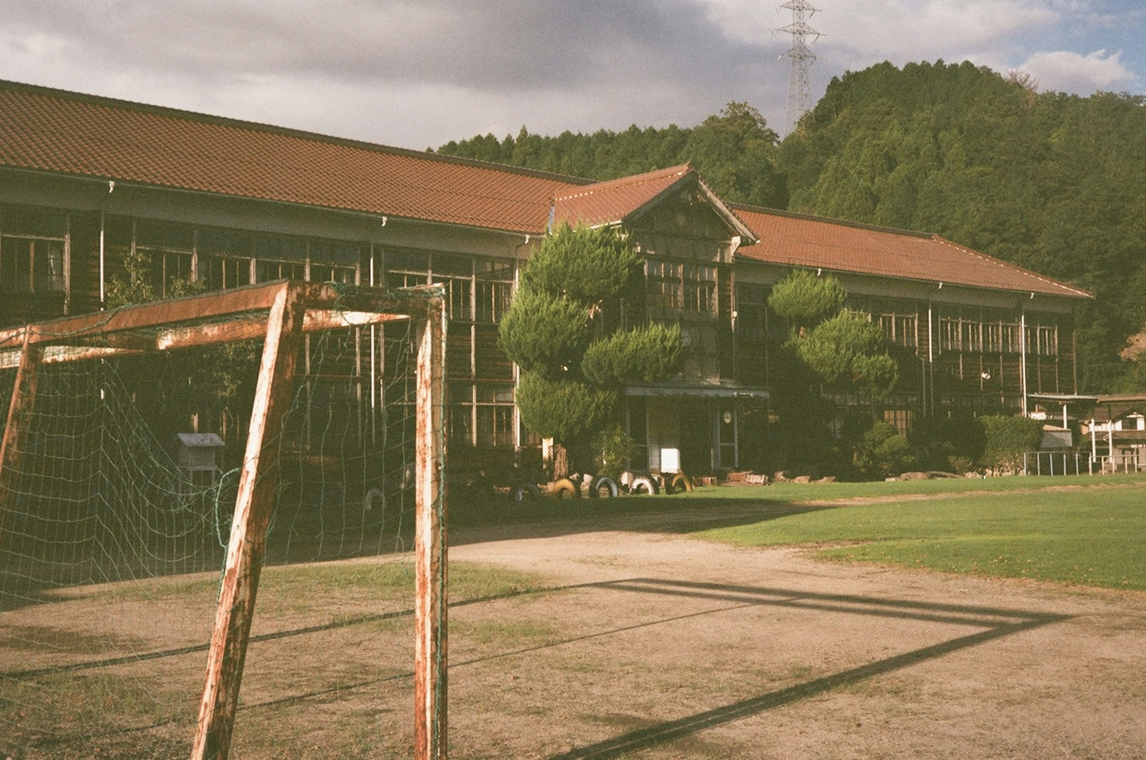 Historisches Schulgebäude mit einem Fußballtor in einer grünen Umgebung