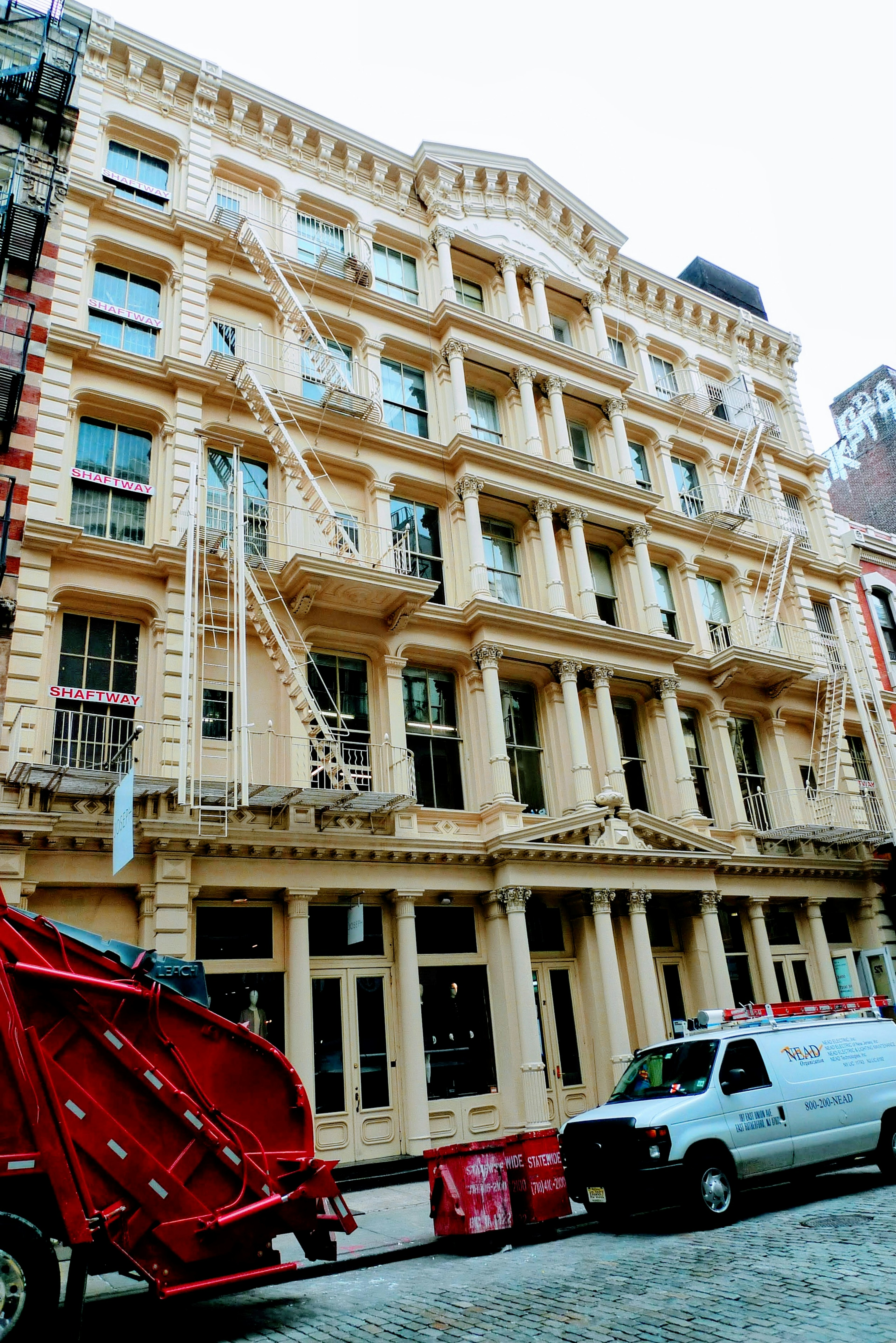 Façade d'un bâtiment historique à Soho New York avec un camion à déchets rouge et une fourgonnette blanche