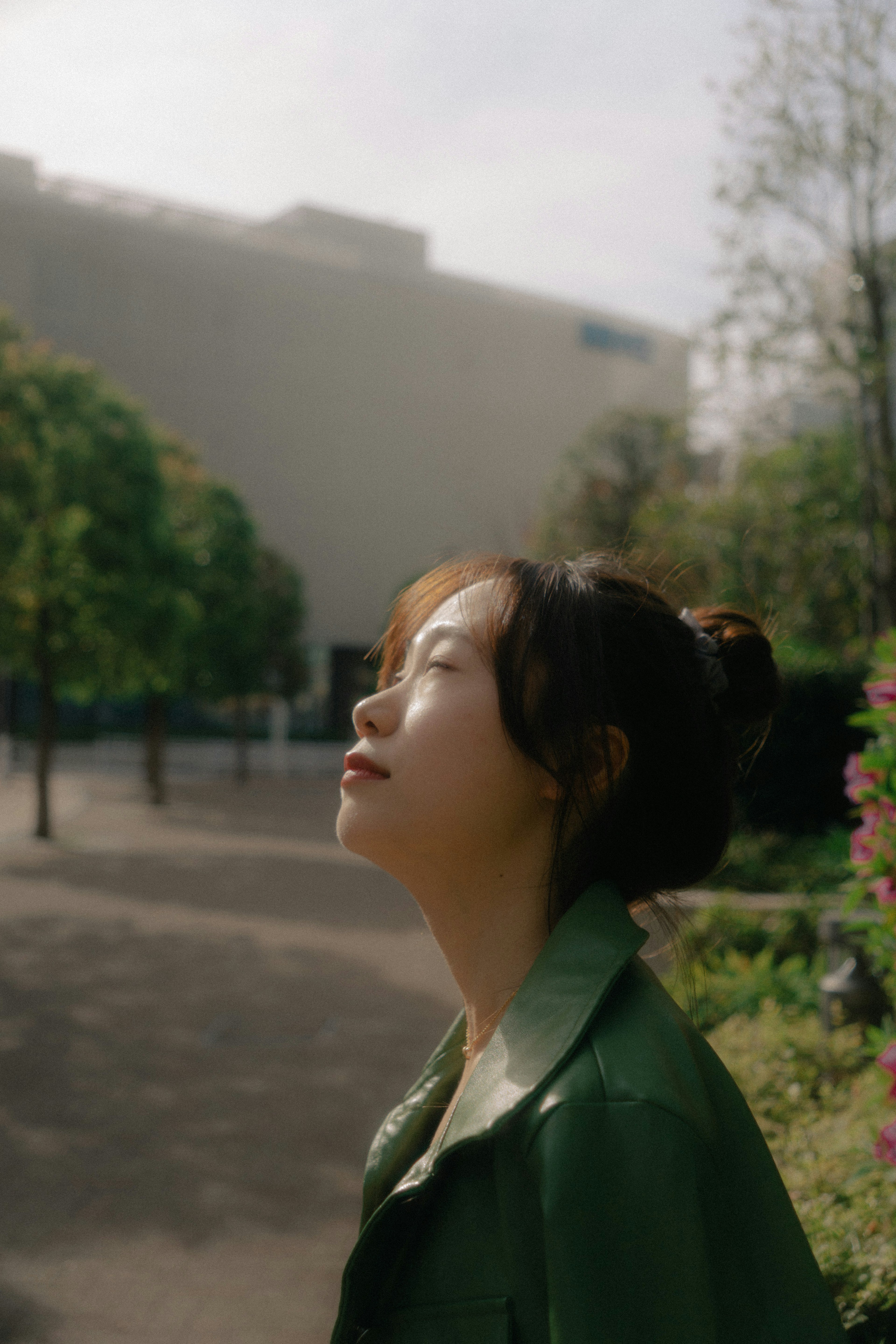 Une femme en manteau vert regardant le ciel dans un jardin