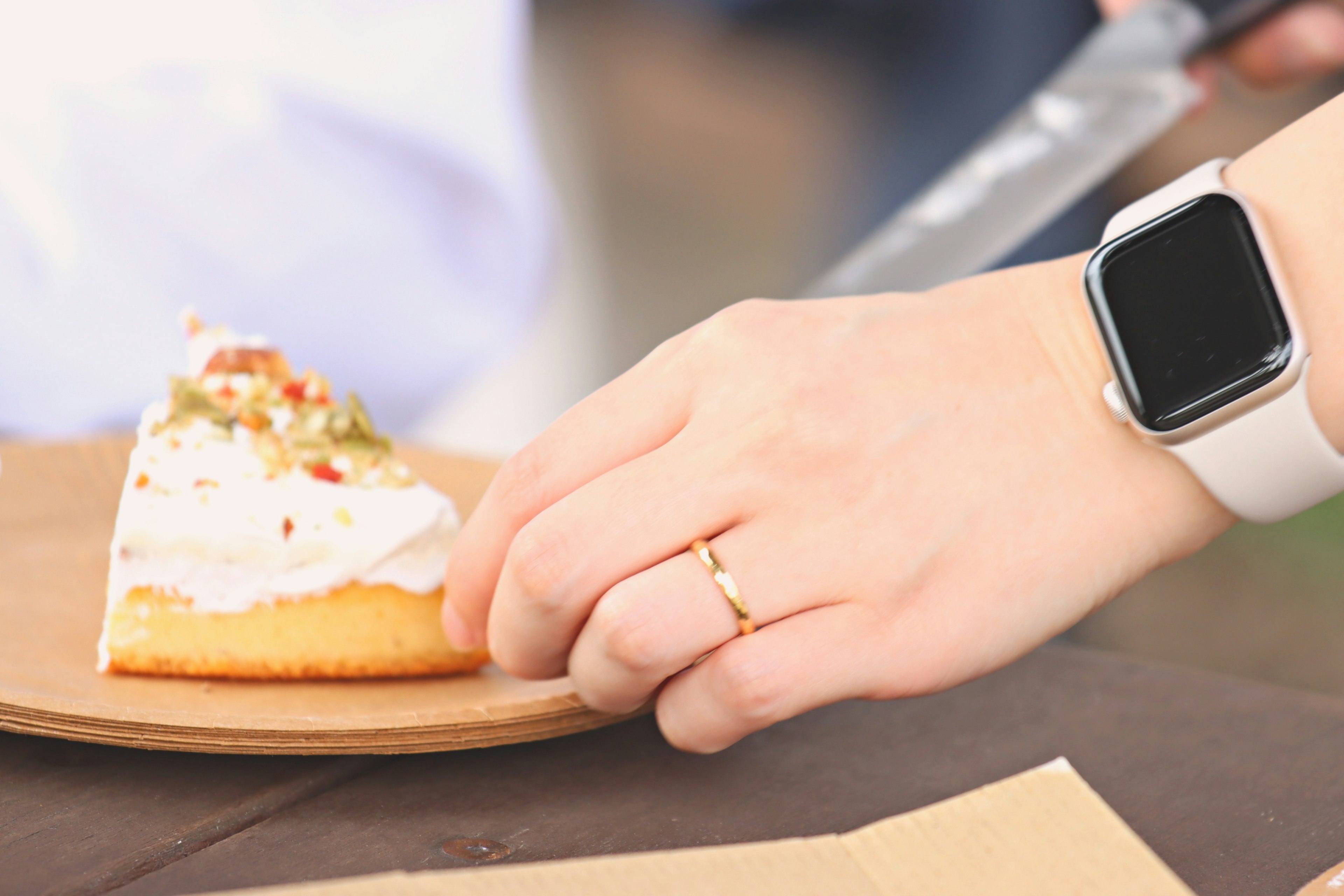 Una mano che tiene una fetta di torta con un orologio intelligente al polso