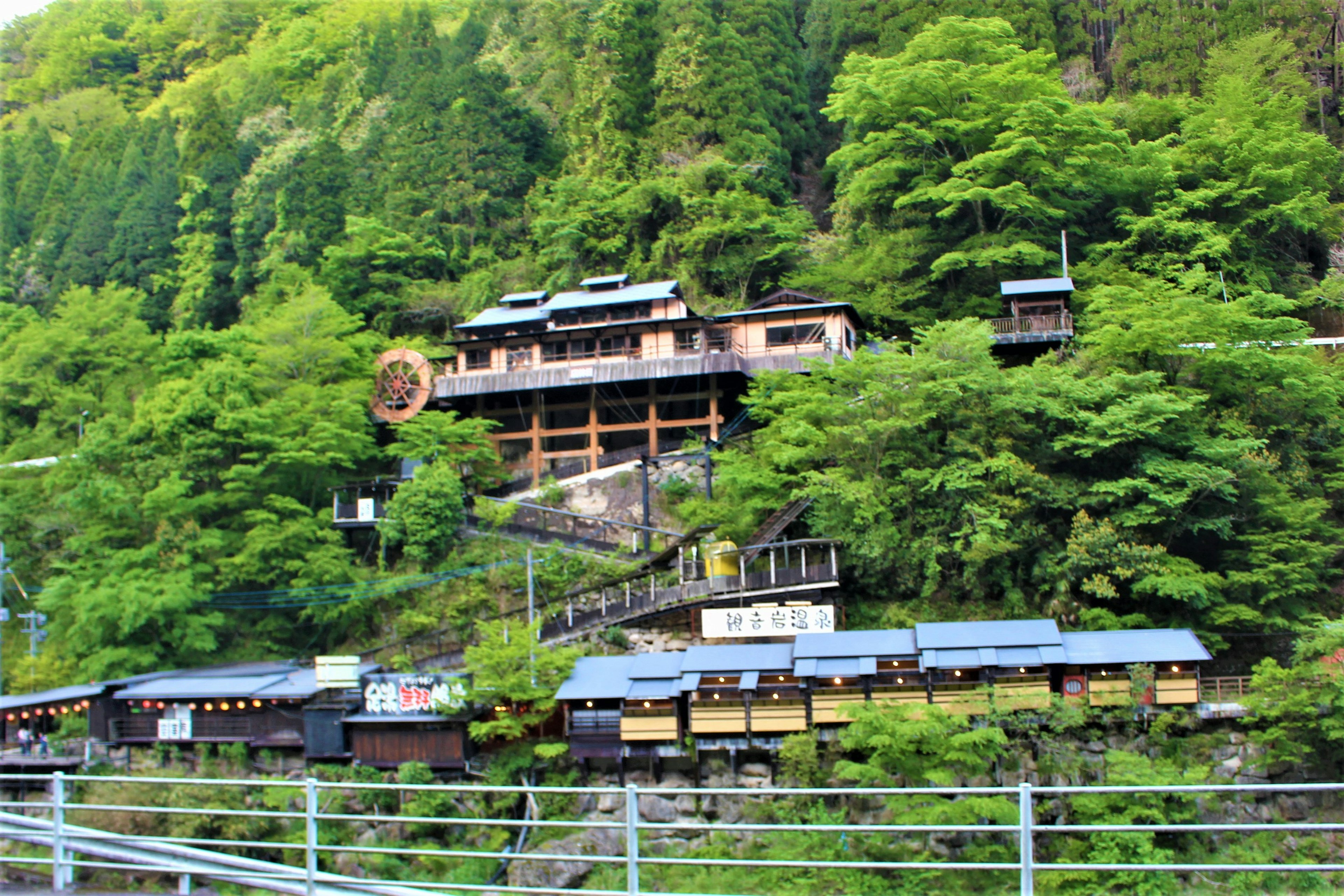 緑に囲まれた山の中に立つ伝統的な日本の旅館とその周辺の建物