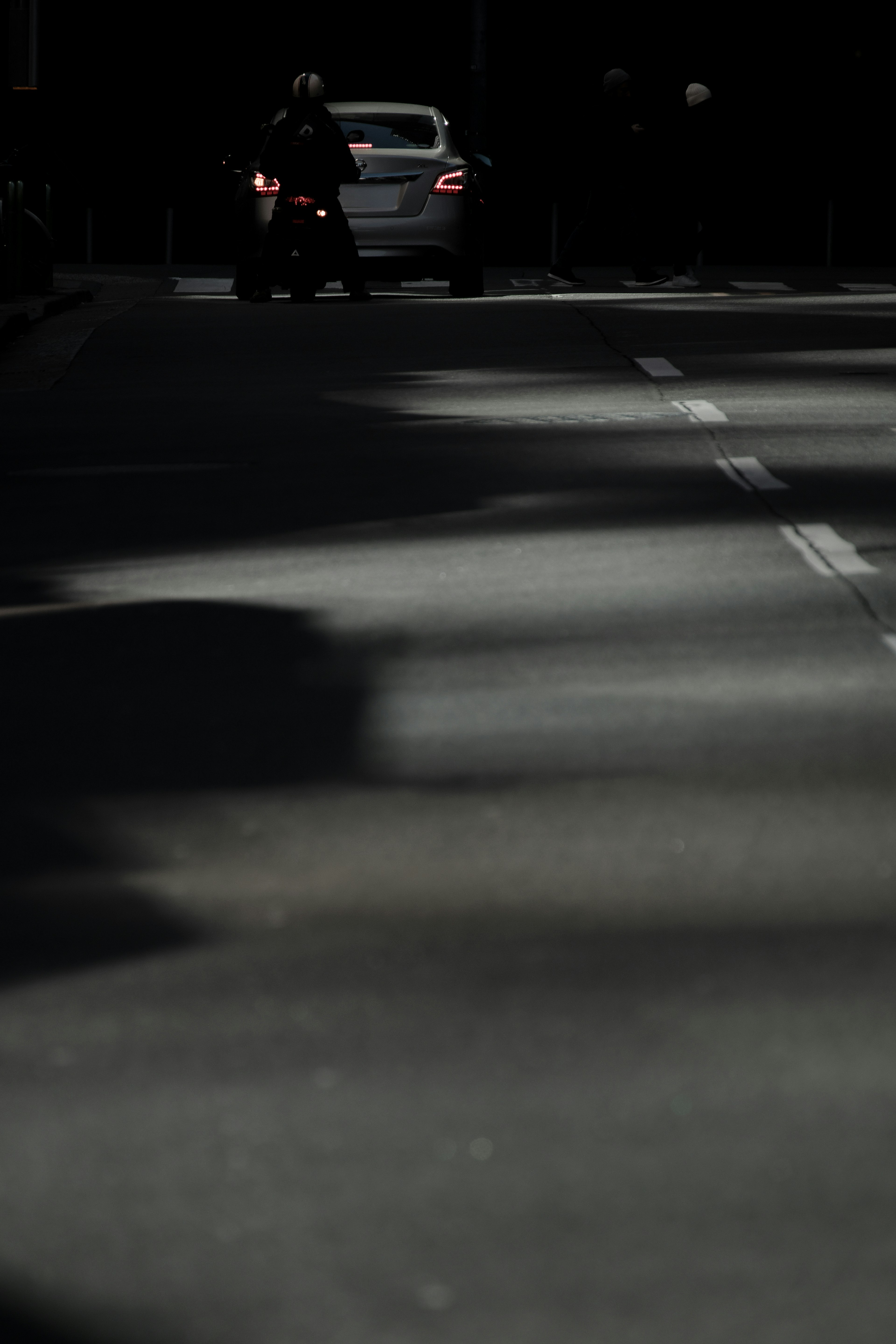 Scene of a dark road featuring a car and a motorcycle