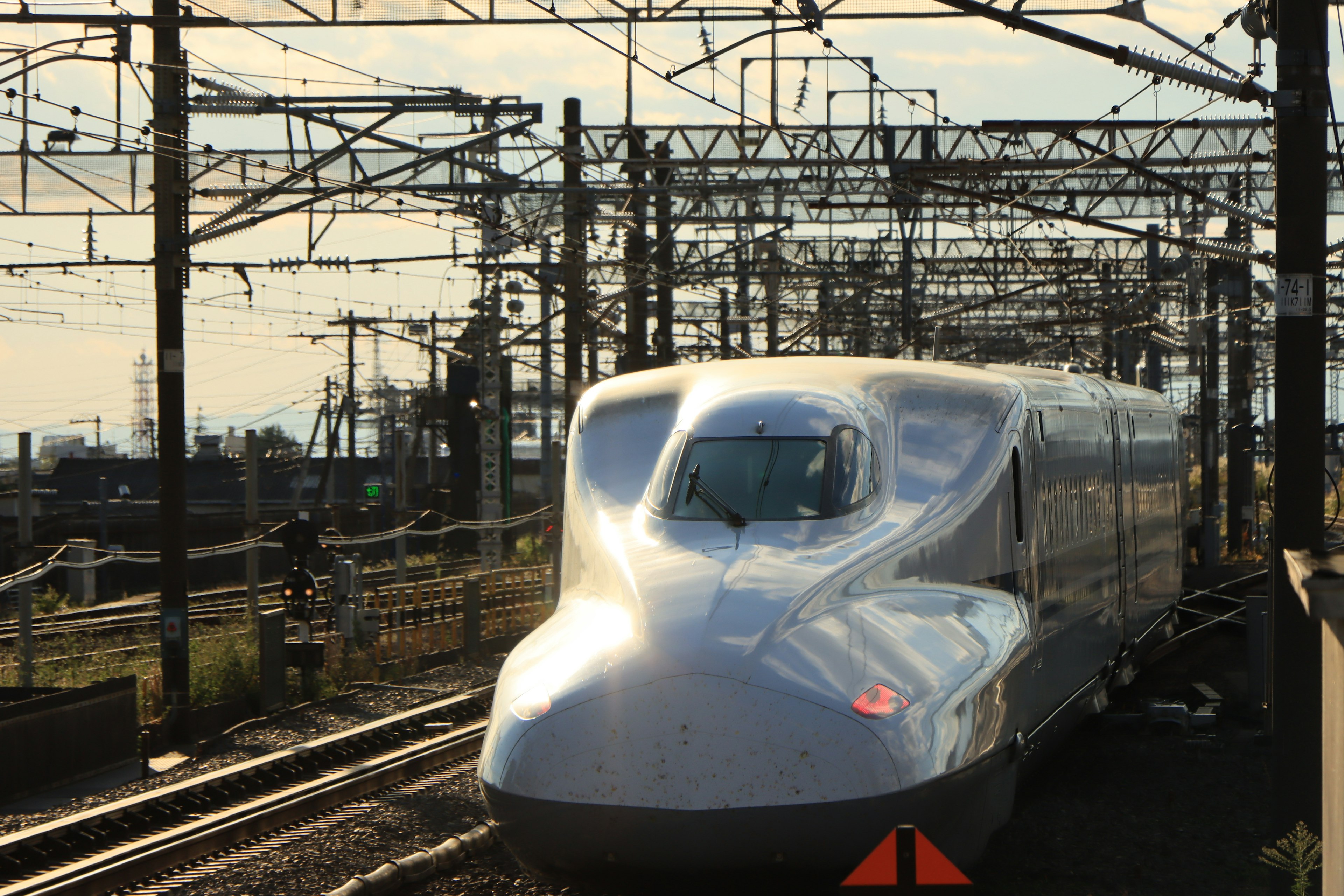 Tren Shinkansen en movimiento con cables aéreos y postes al fondo