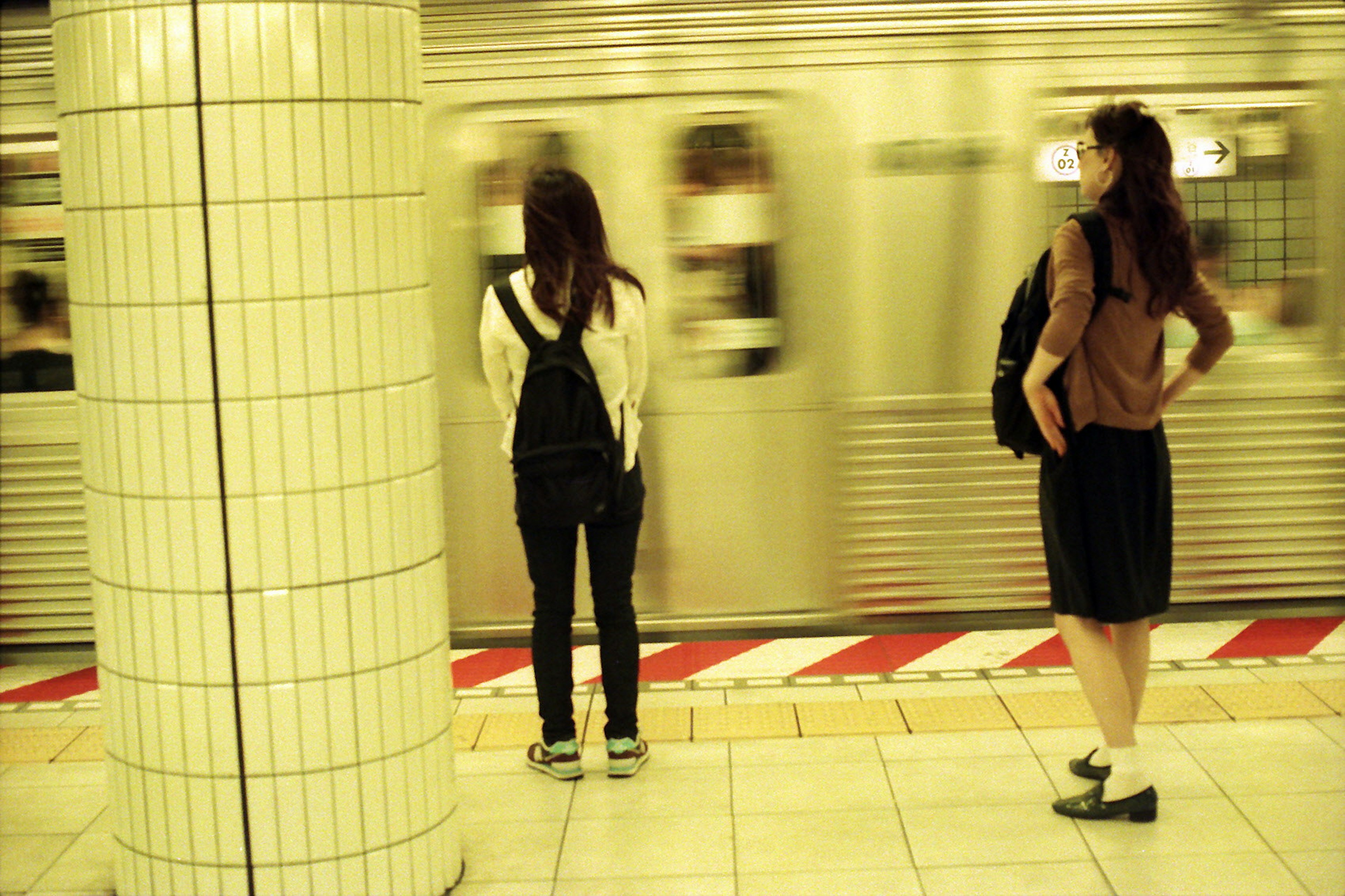 Two women waiting for a subway train in a station