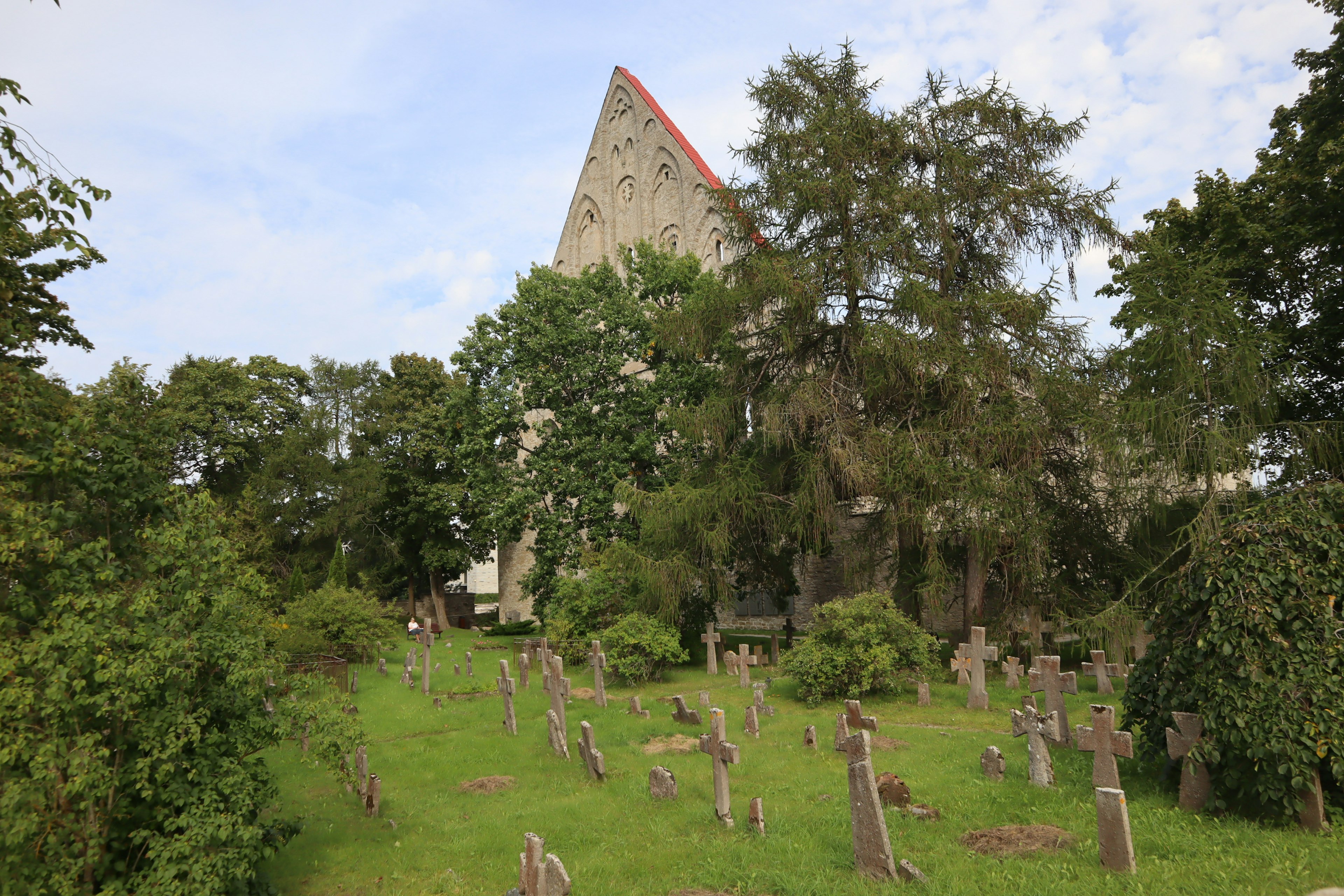 Cementerio con lápidas esparcidas sobre hierba verde cerca de una iglesia antigua