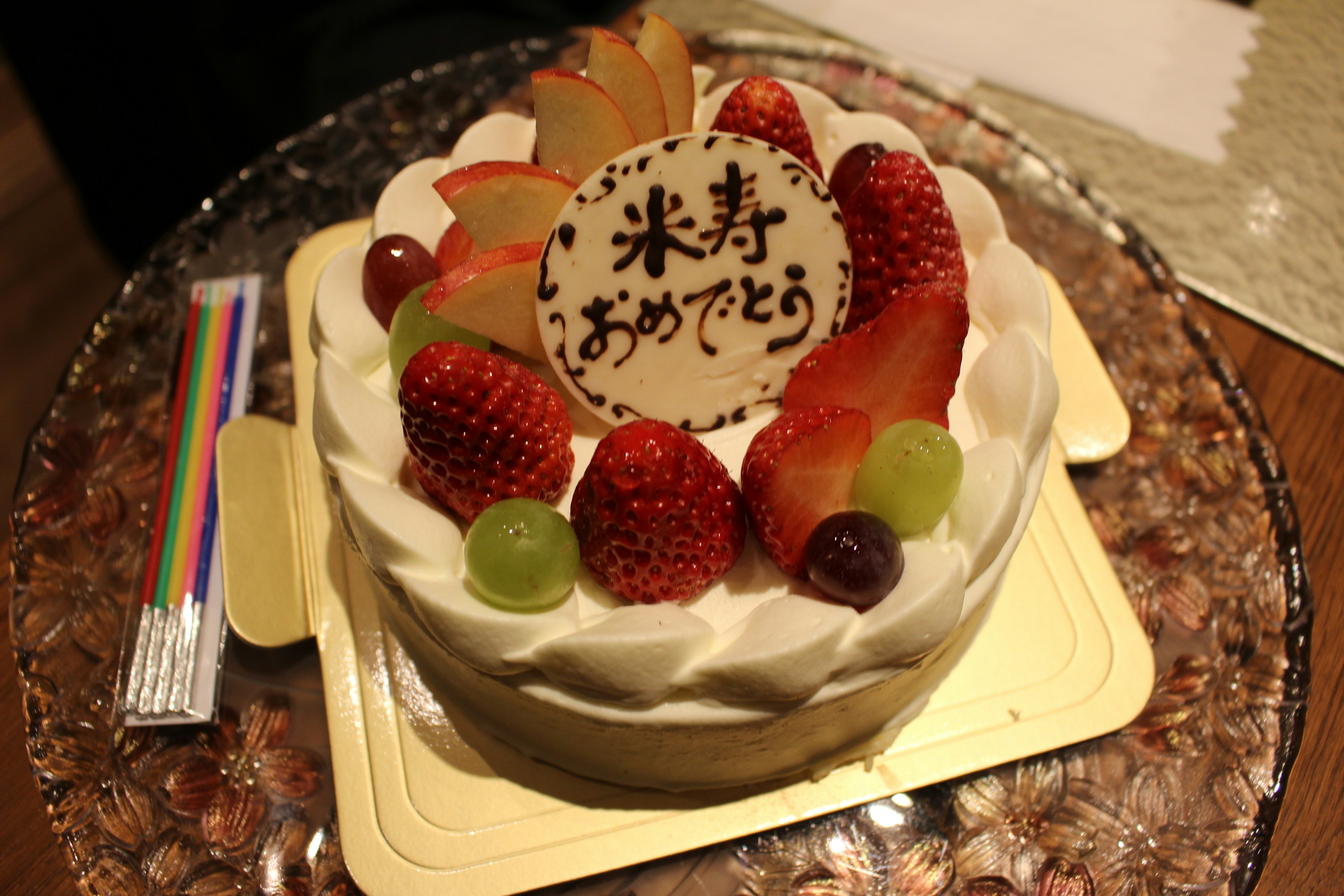 Un pastel decorado con frutas y crema que presenta un mensaje de felicitación