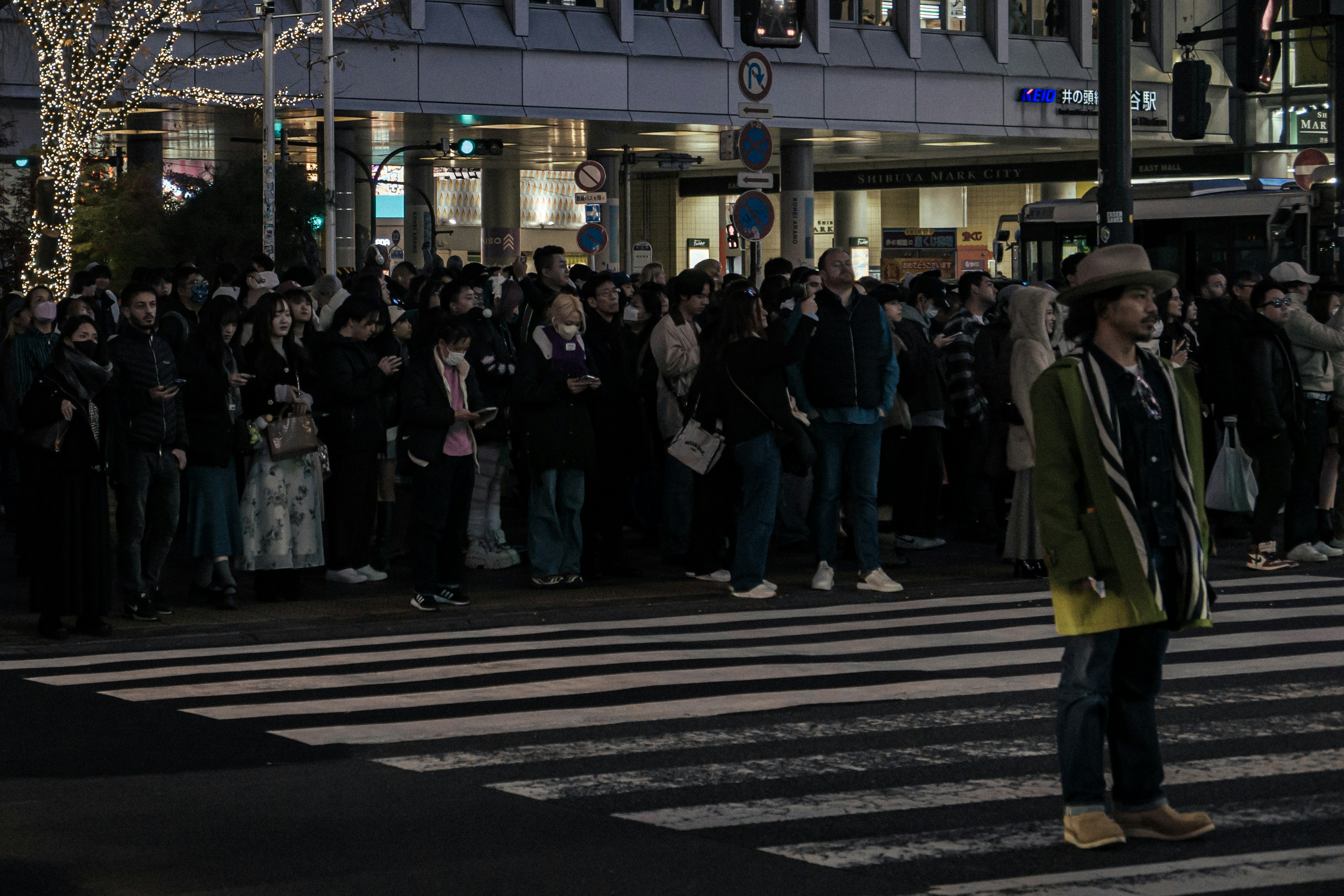 夜の交差点に立つ人々の群れと一人の男性