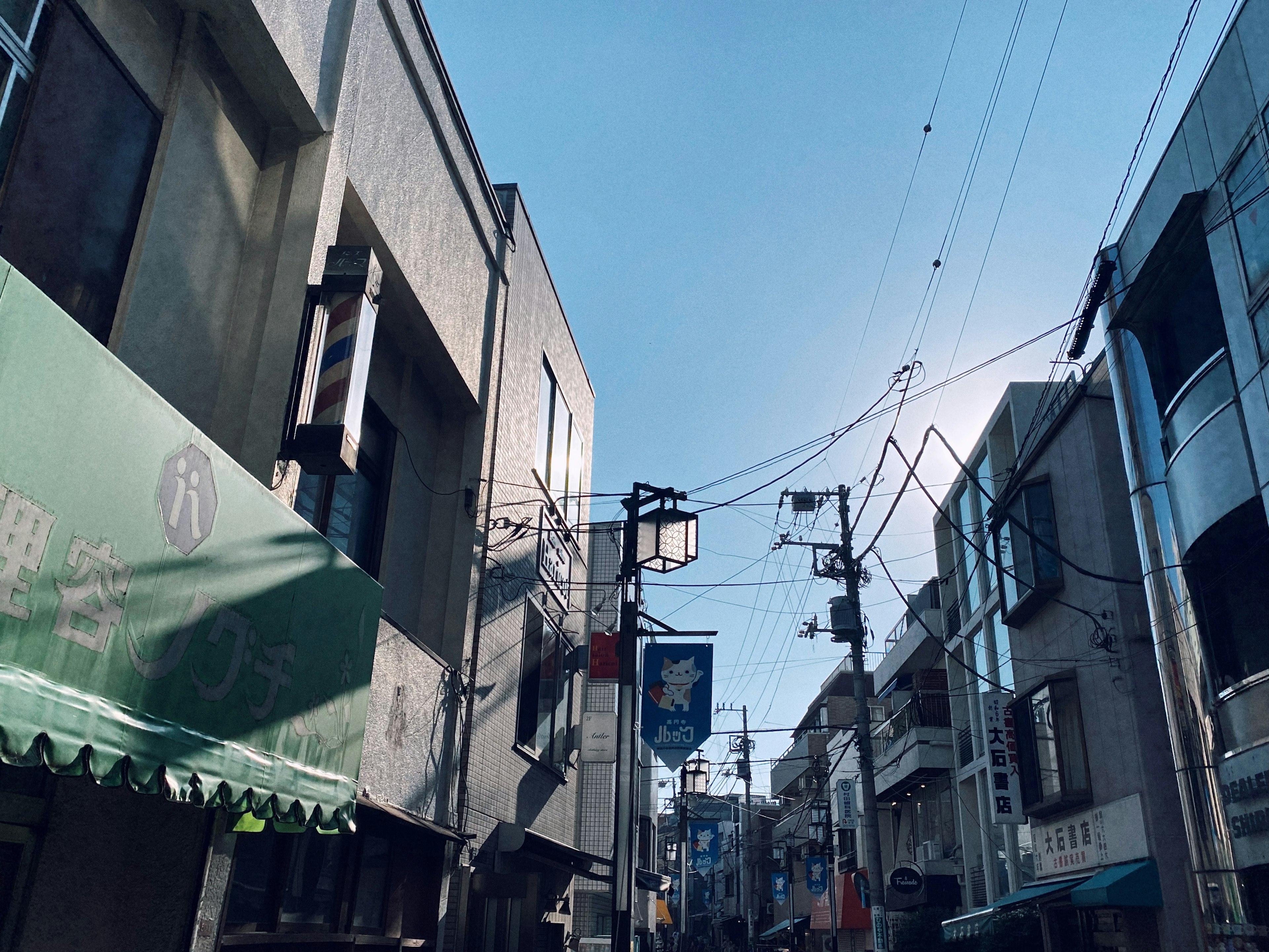 Escena urbana bajo un cielo azul claro con edificios y líneas eléctricas