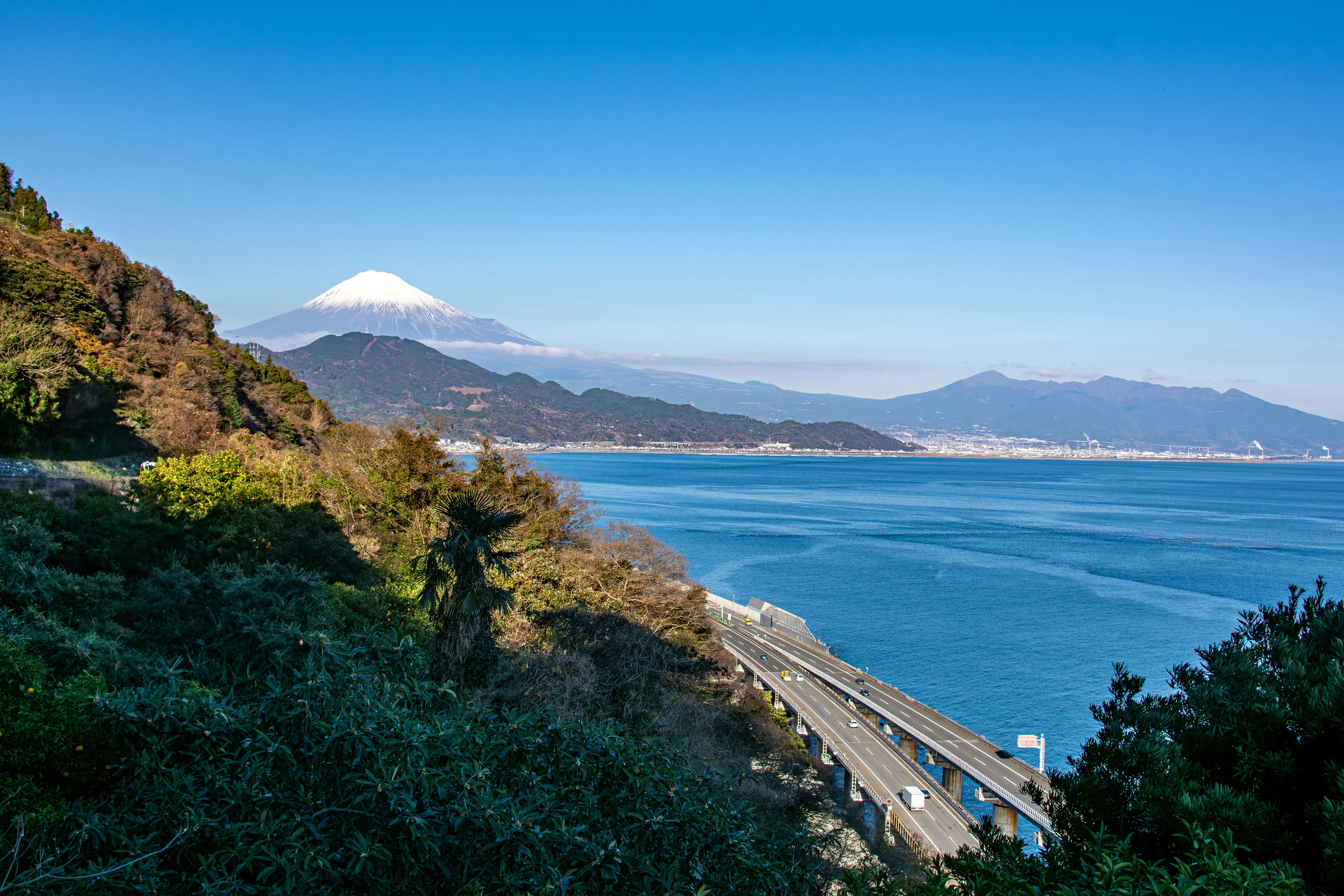 Vista panoramica del monte Fuji e dell'oceano con colline verdi e cielo blu chiaro