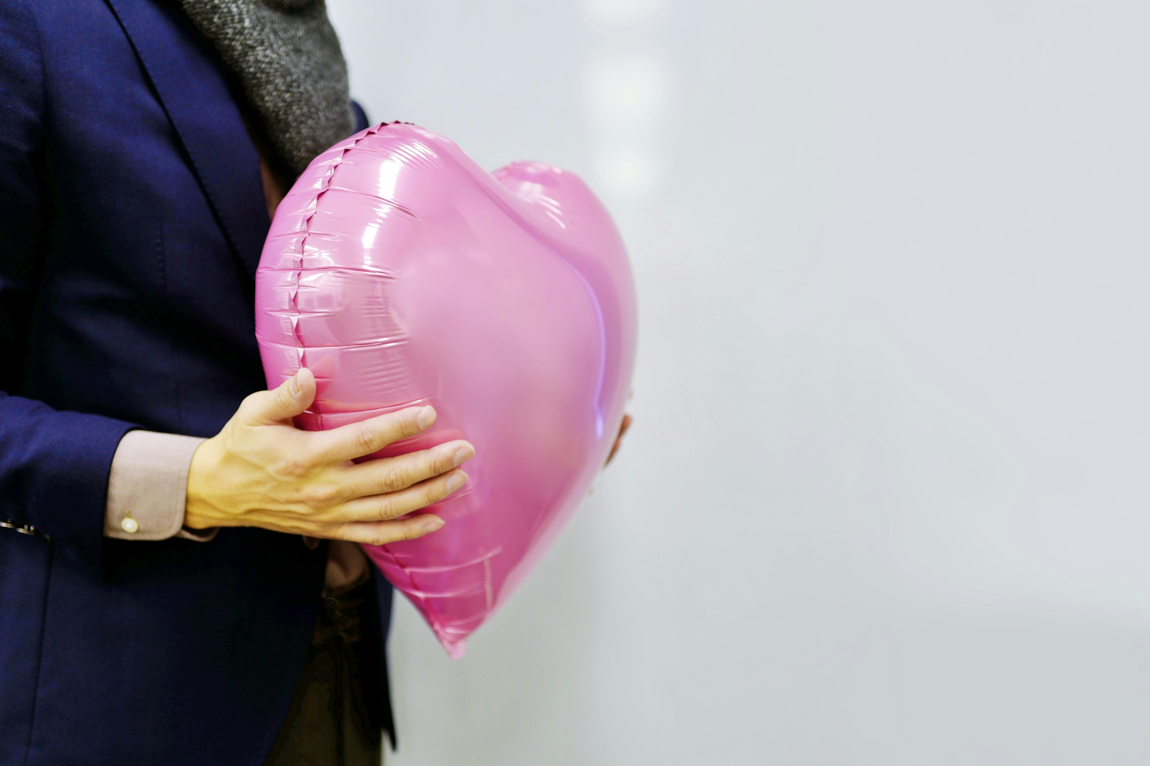 A person holding a pink heart-shaped balloon