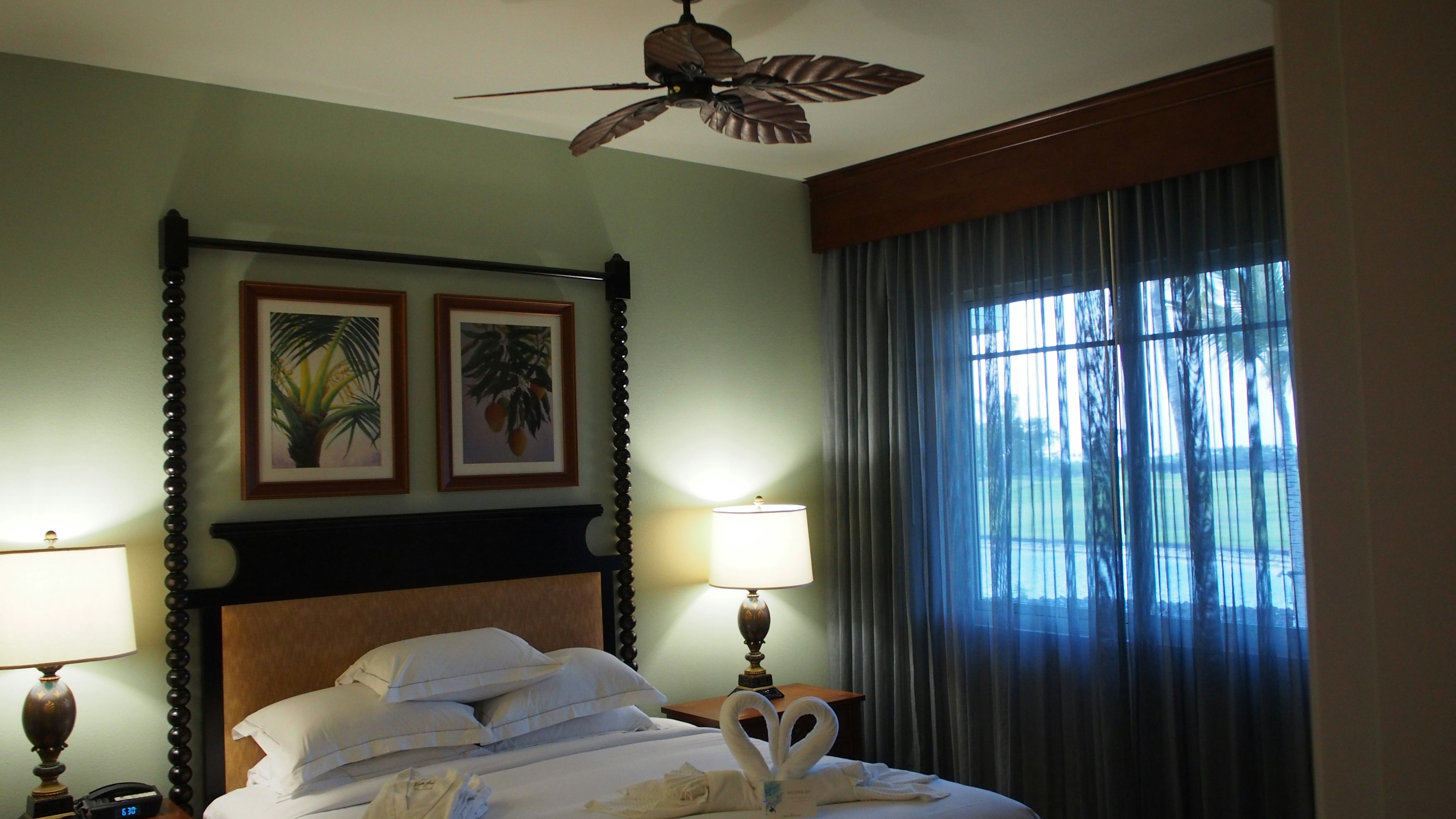 Cozy bedroom featuring a bed with decorative fan and artwork