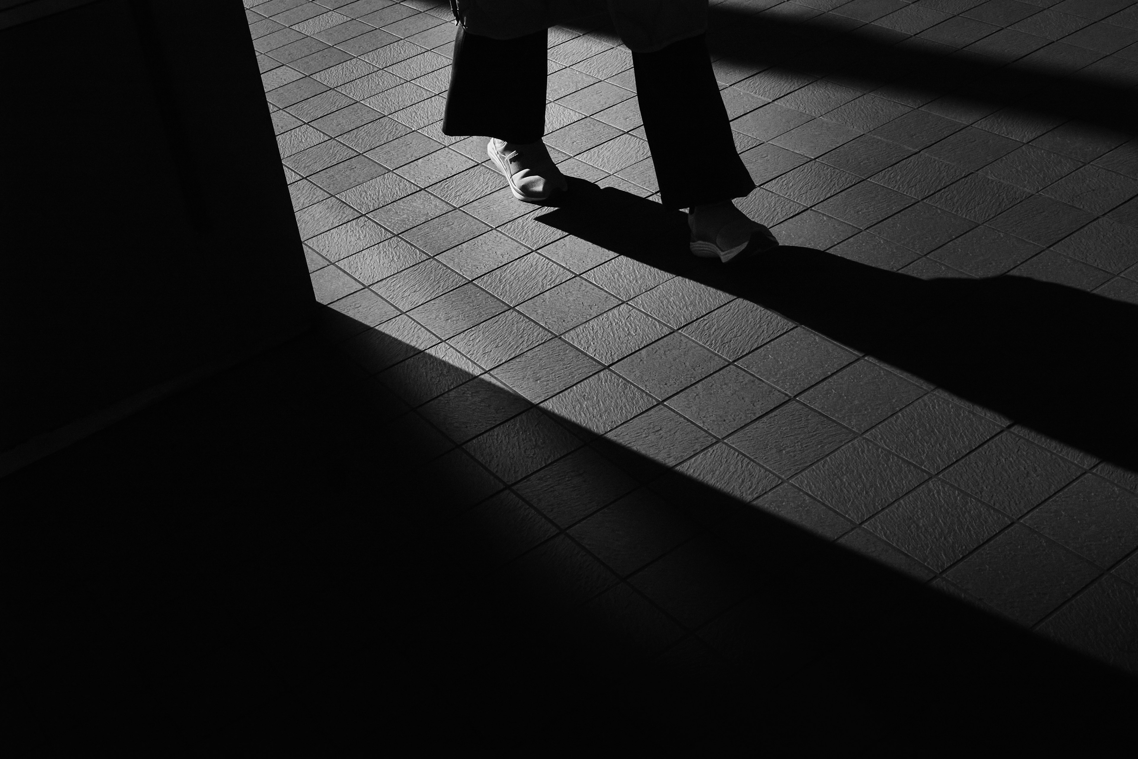 A striking black and white image showing a person's feet walking with a prominent shadow