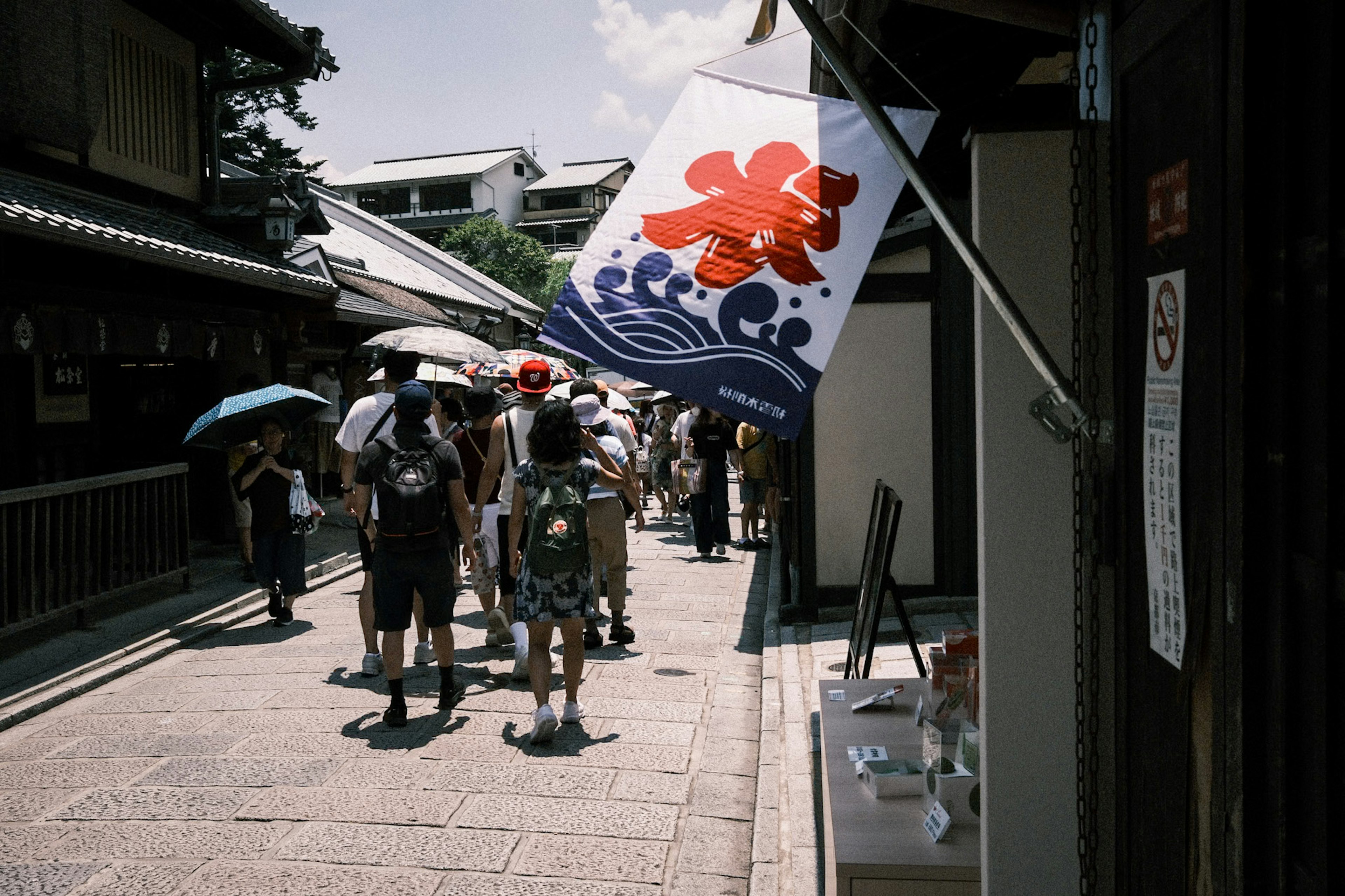 人々が傘を持って歩く伝統的な日本の街並みと旗