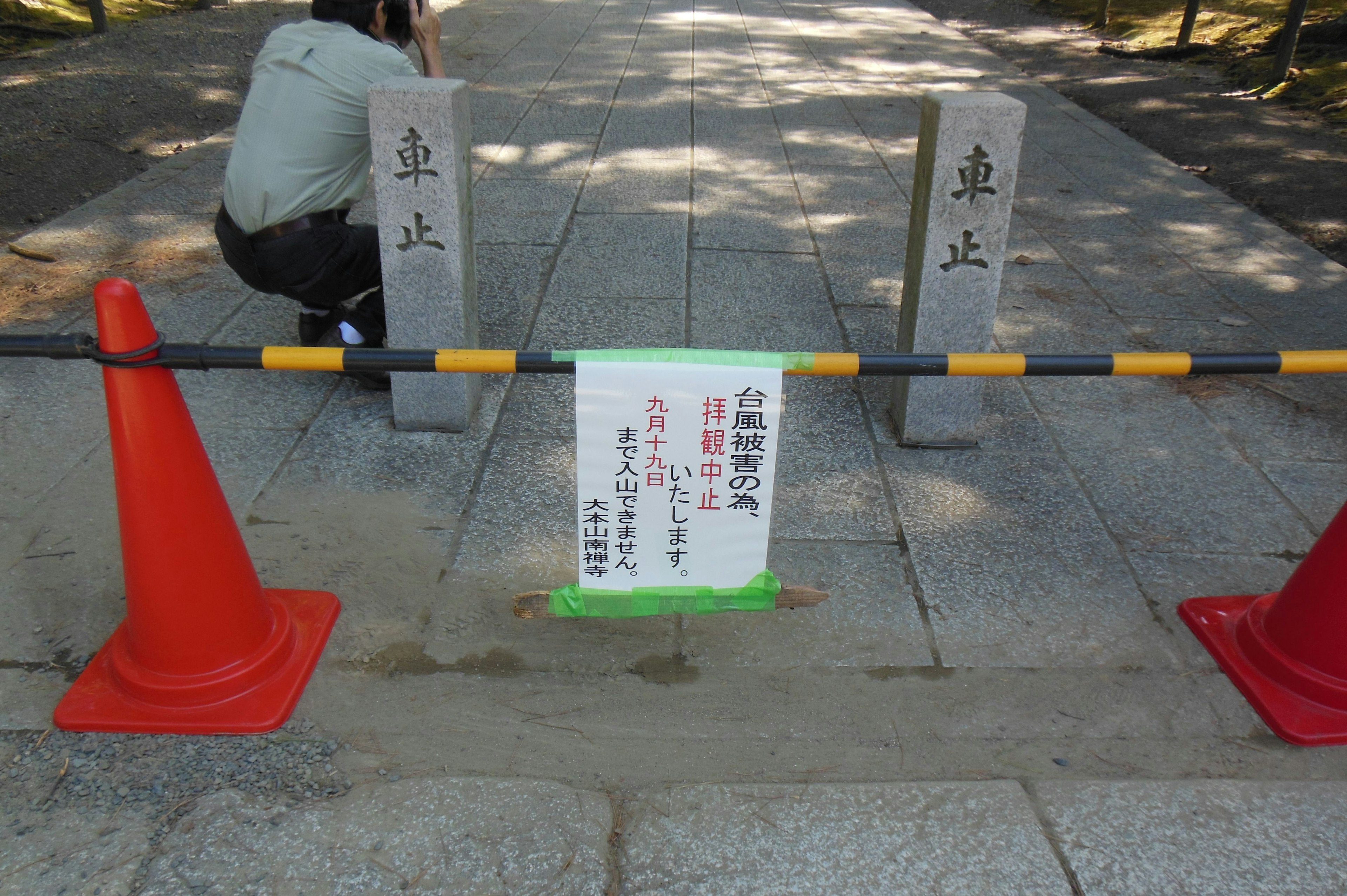 Stone-paved path blocked by red cones and a prohibition sign