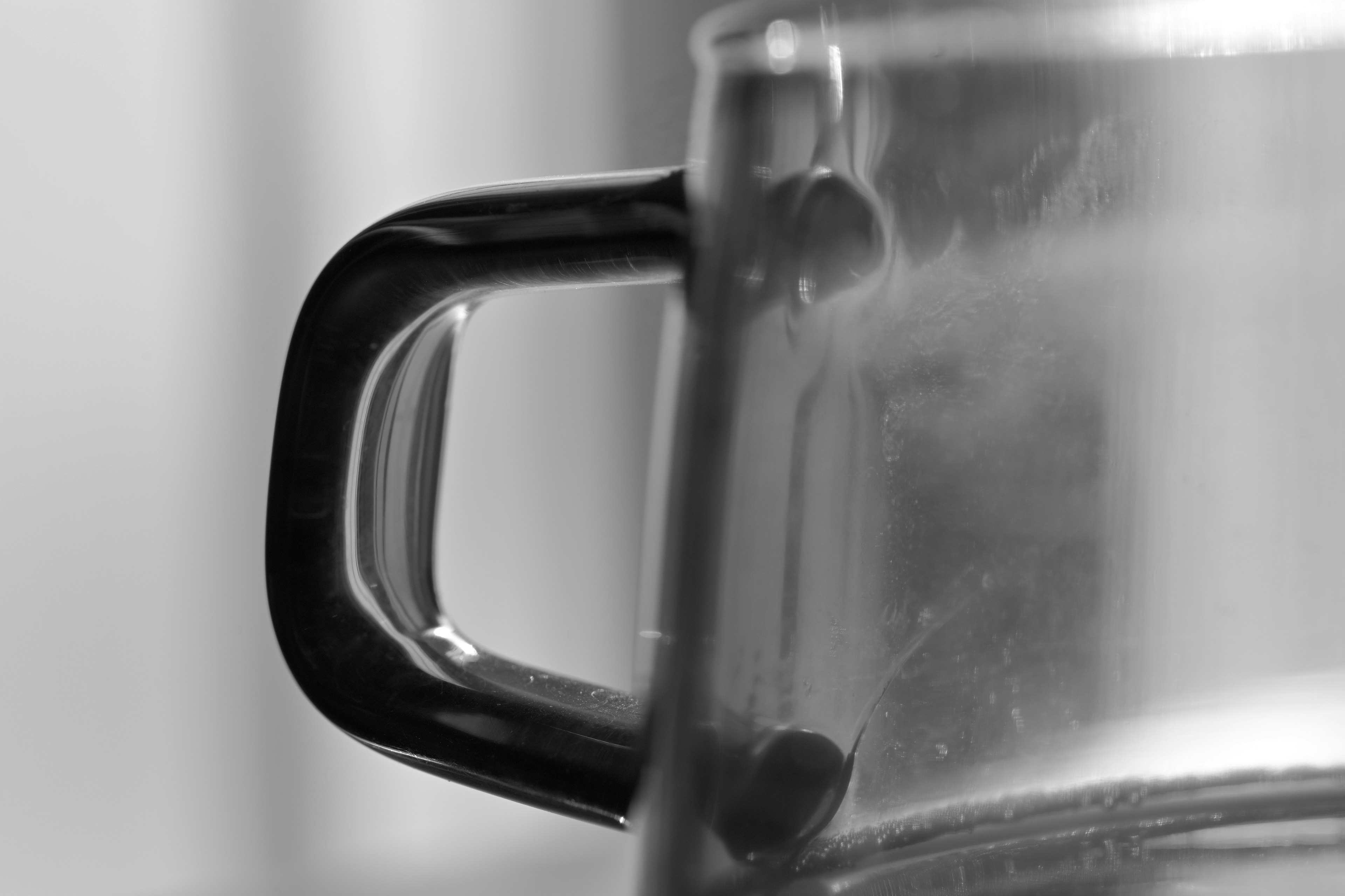 Close-up of a transparent glass container with a black handle