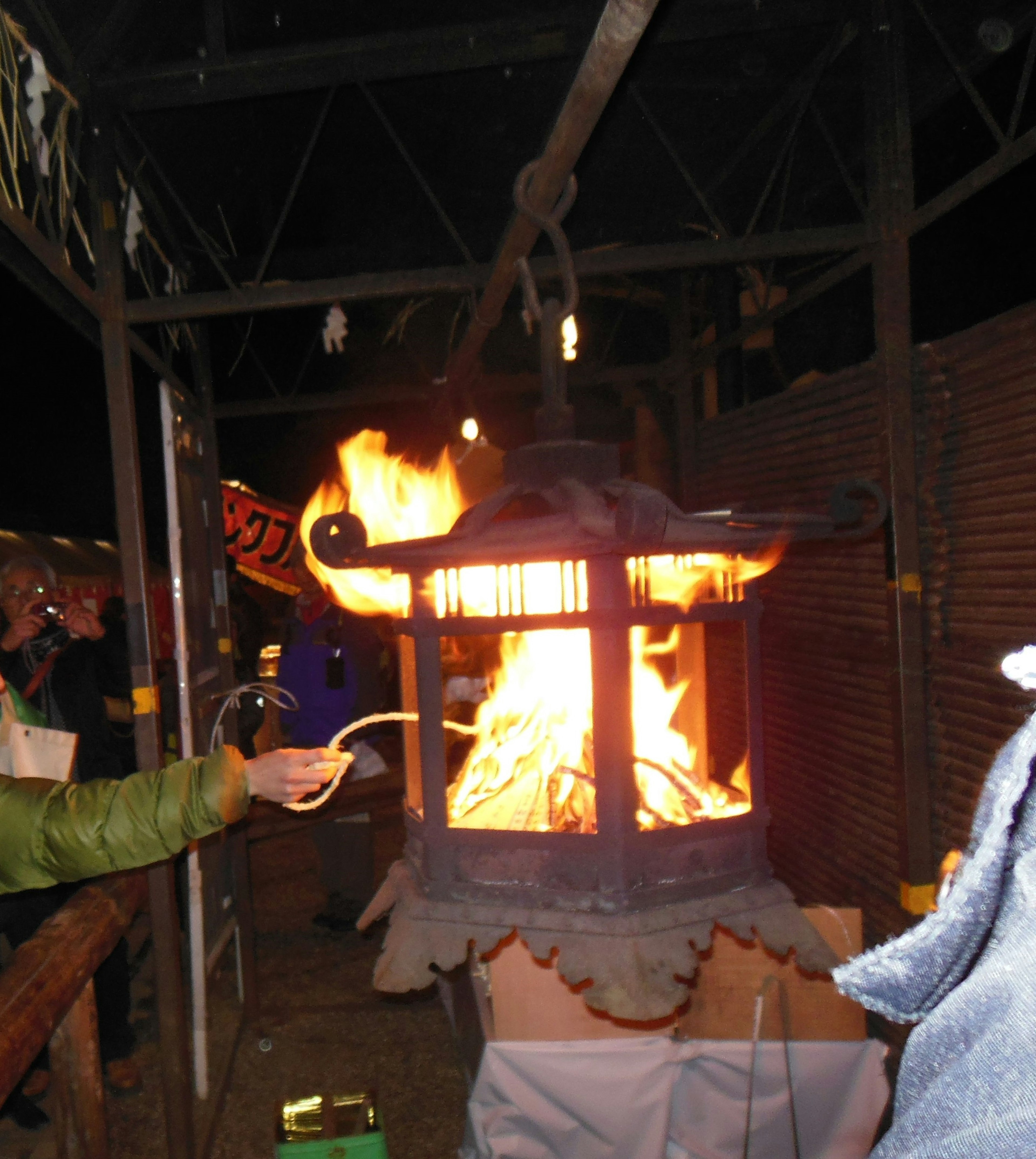 People gathered around a traditional lantern with flames