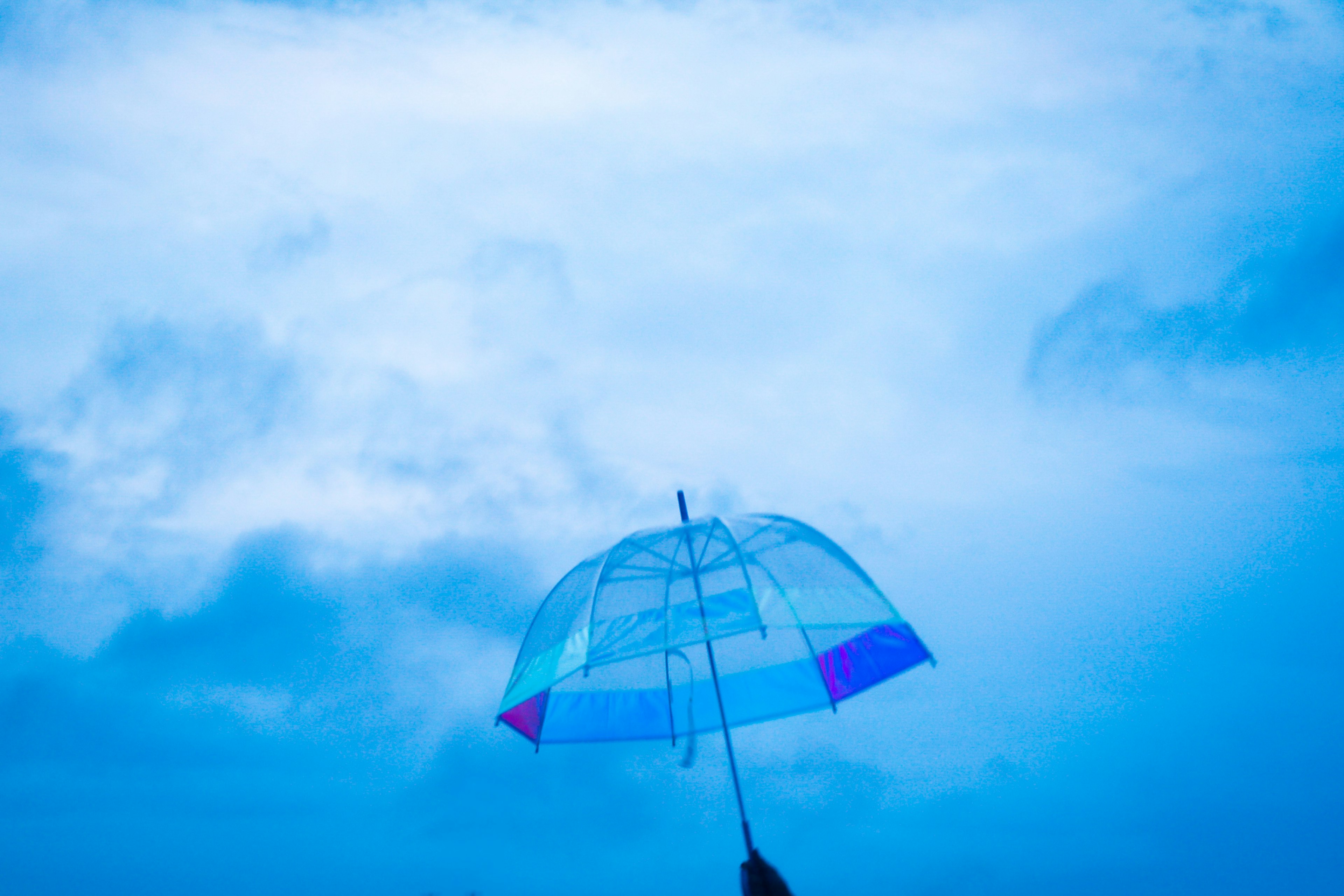 Imagen de un paraguas transparente sostenido contra un cielo azul