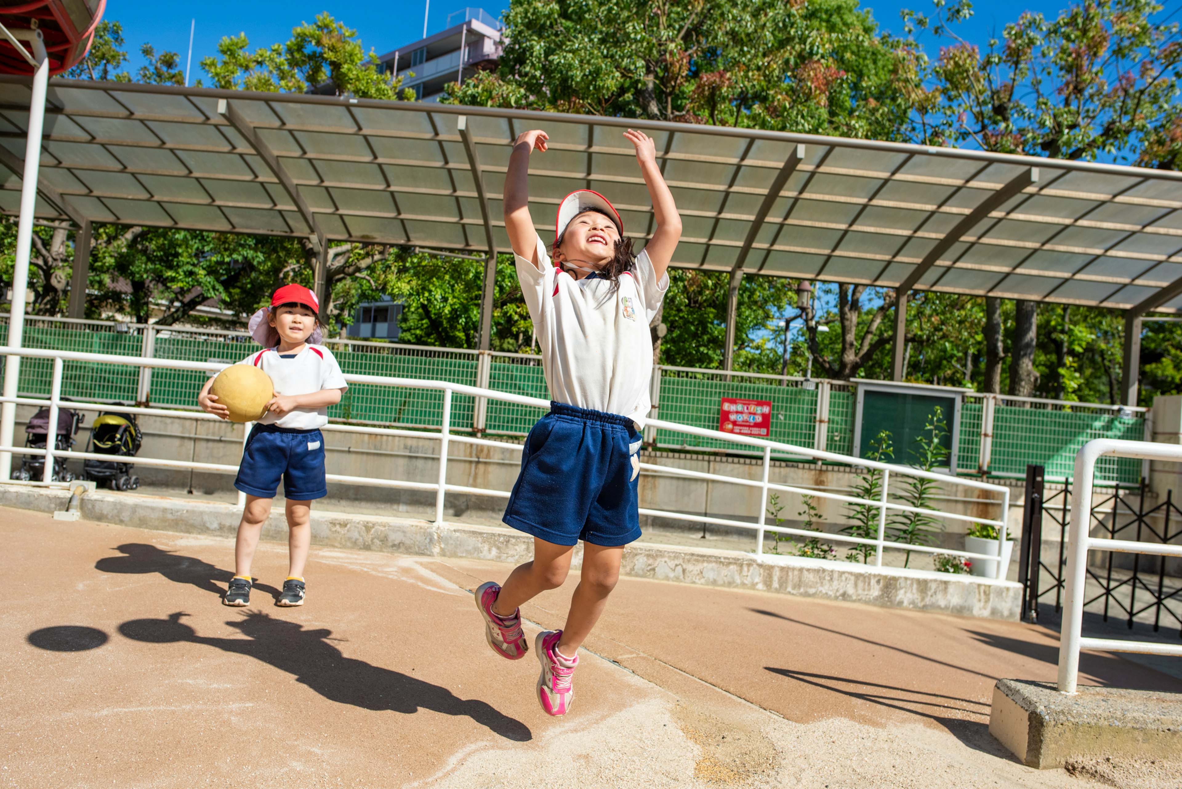 Children playing in a park scene with one child jumping joyfully