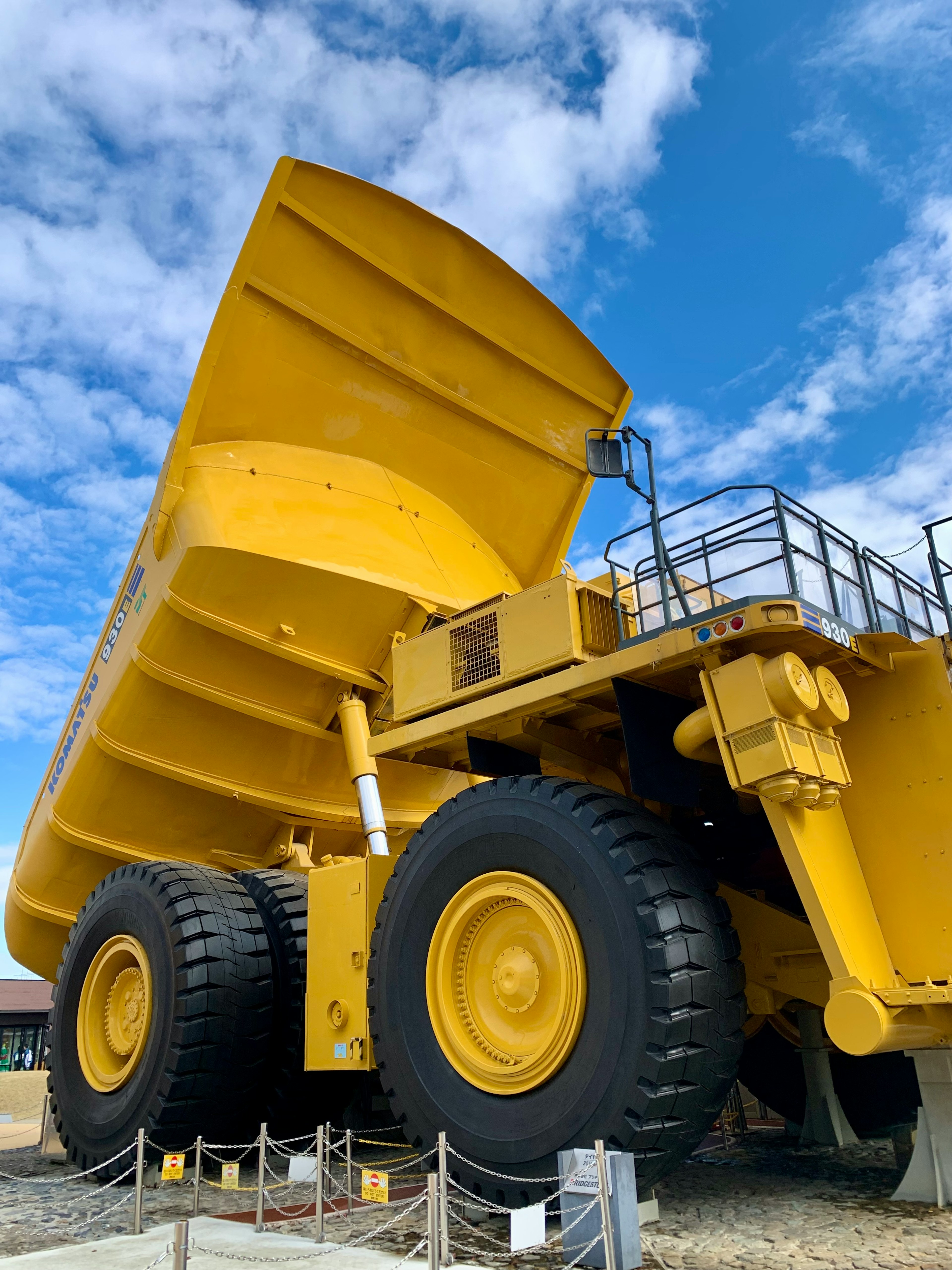 Grand camion benne jaune positionné sous un ciel bleu