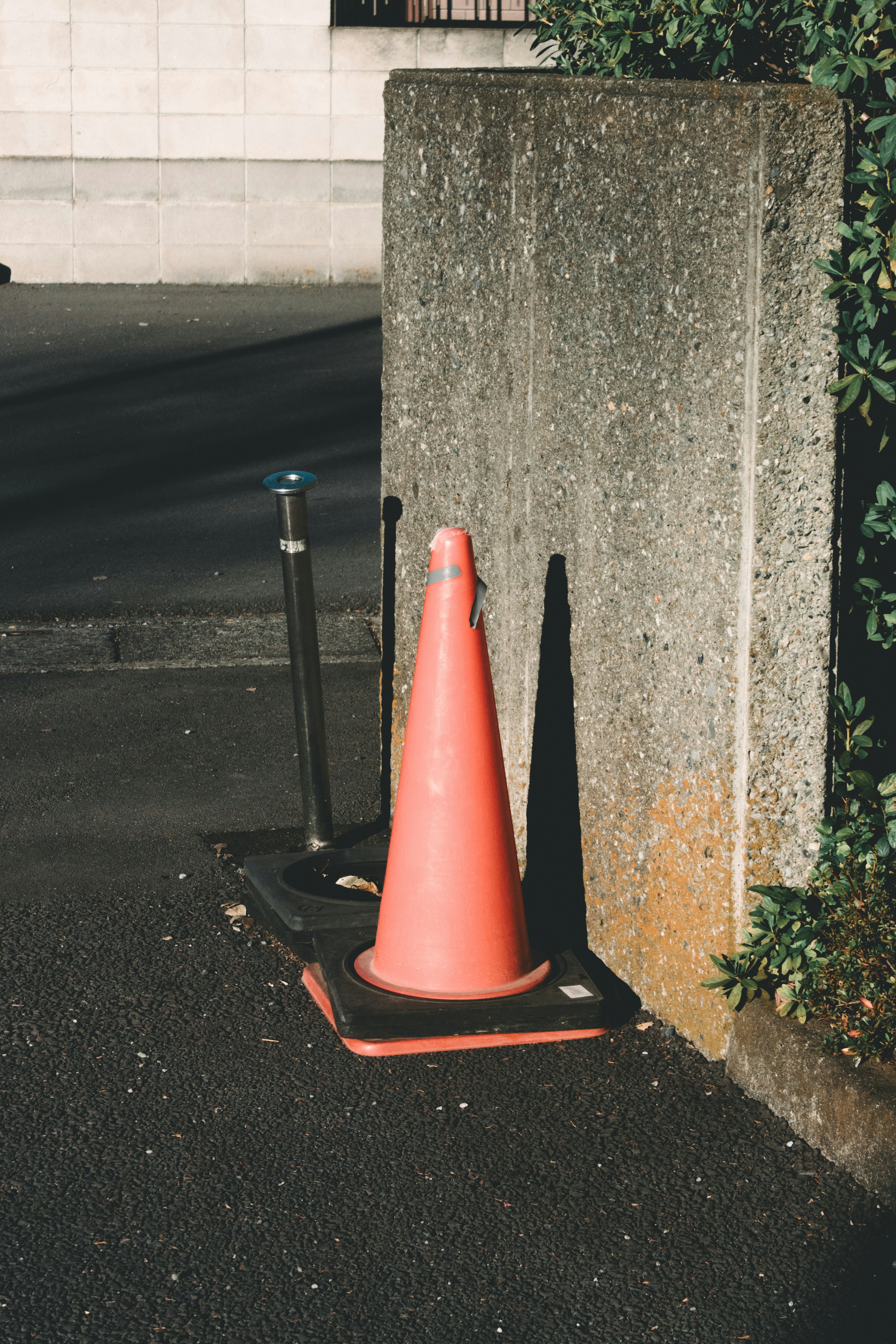 An orange traffic cone placed next to a concrete wall