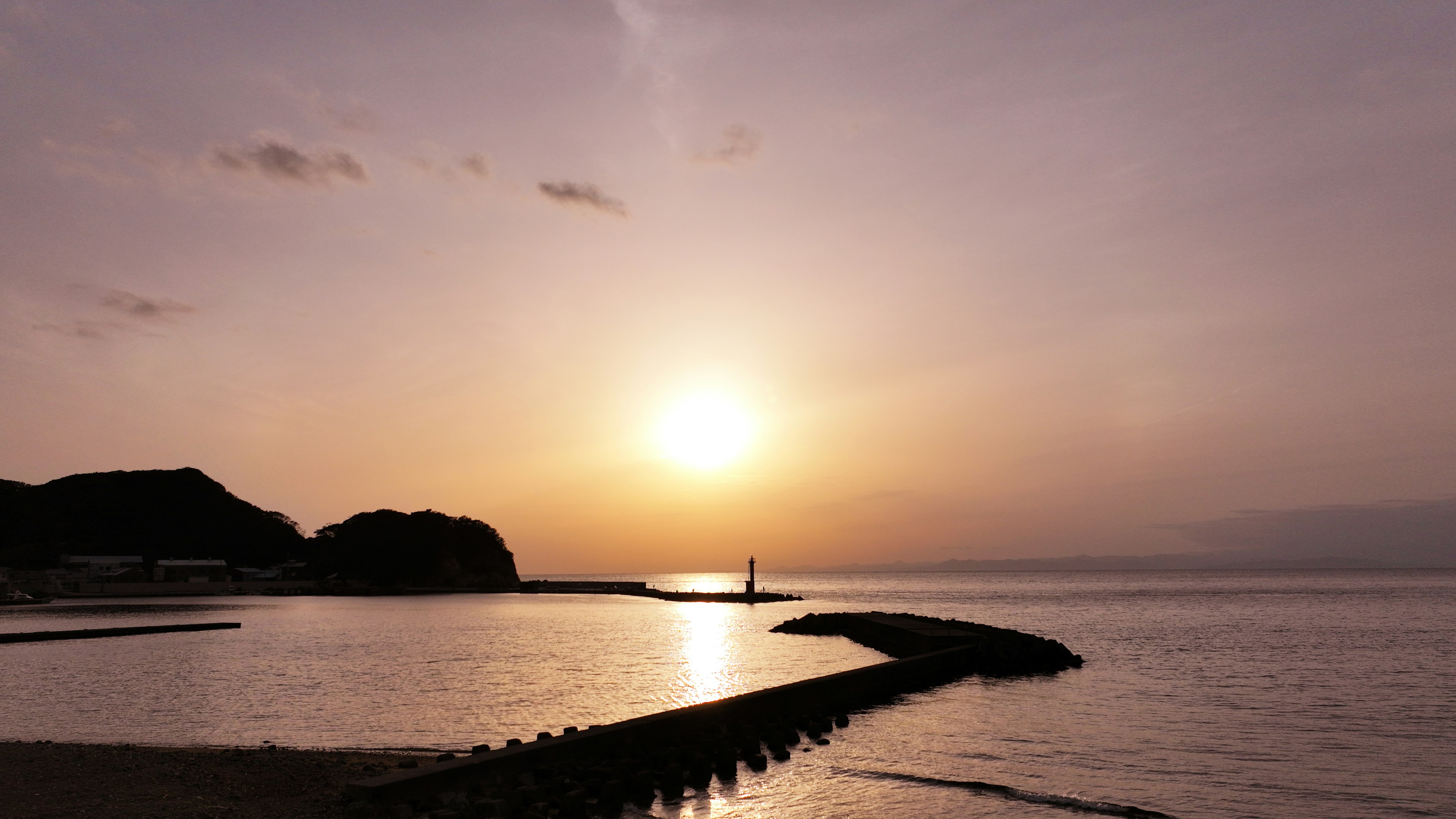 ทิวทัศน์ที่สวยงามของพระอาทิตย์ตกเหนือทะเลพร้อมชายหาดและเขื่อนกันคลื่น