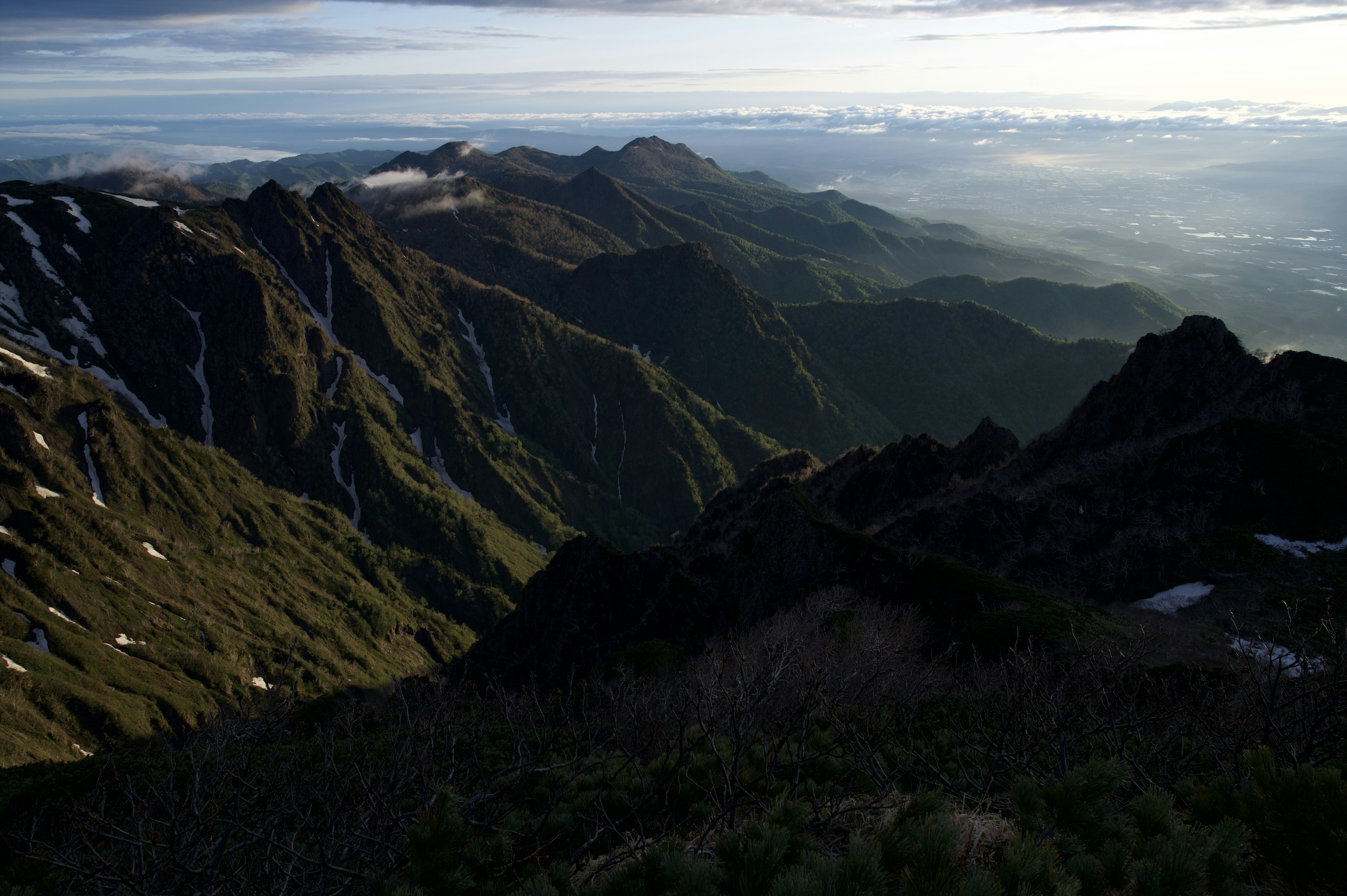 Stunning mountain landscape with lush greenery and patches of snow under a blue sky