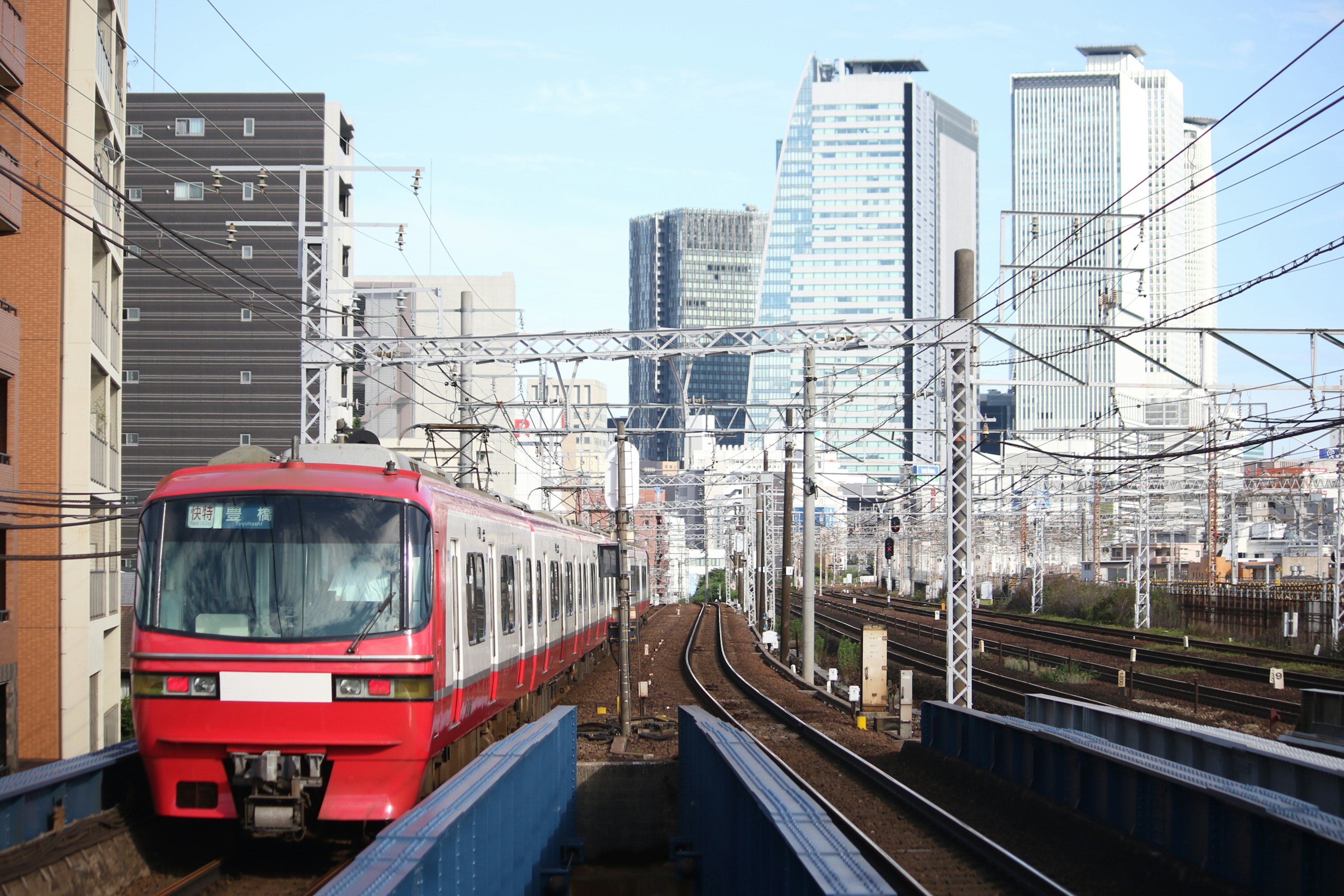 Red train traveling with skyscrapers in the background