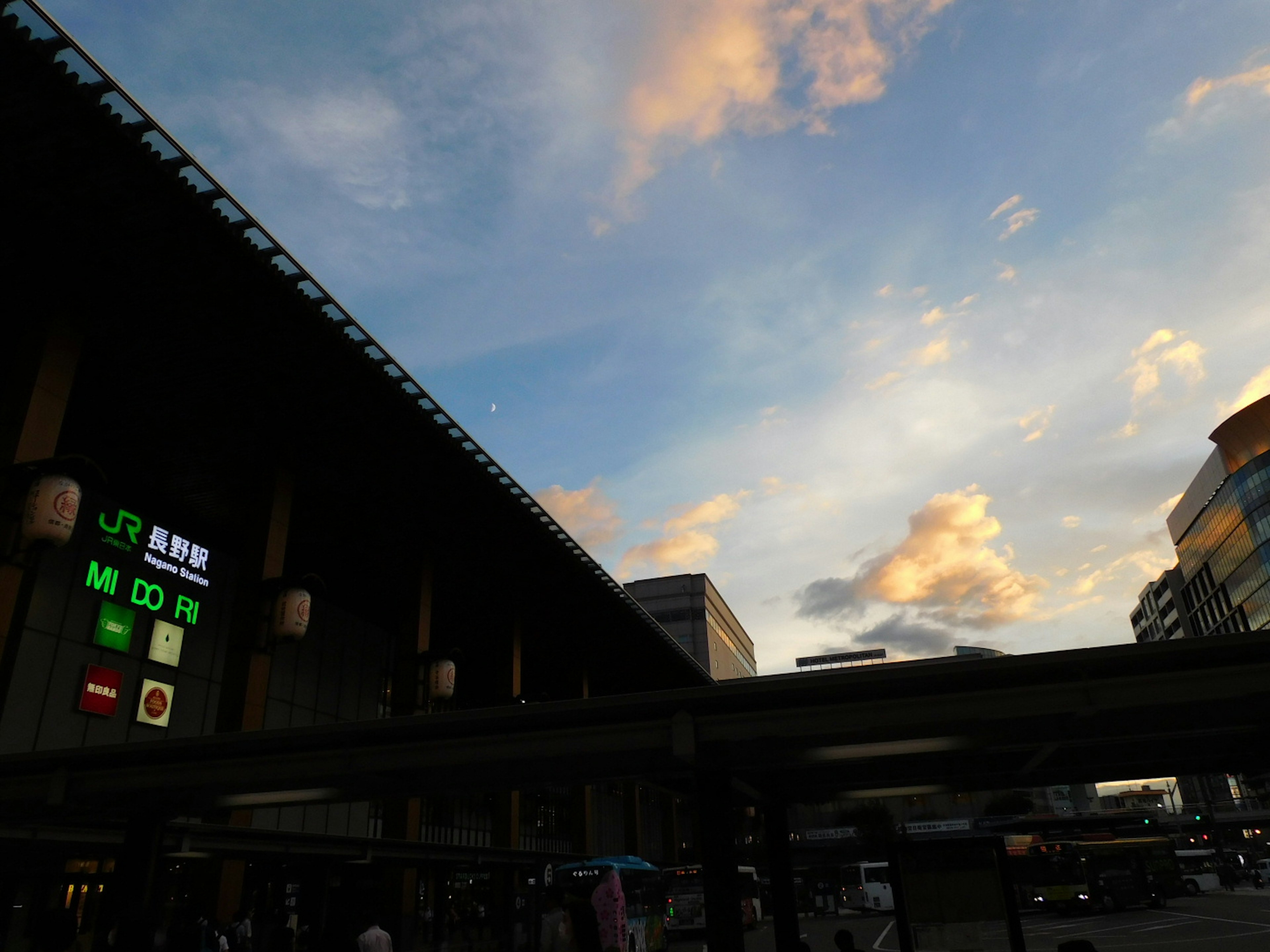 Eksterior stasiun dengan langit senja dan tampilan digital