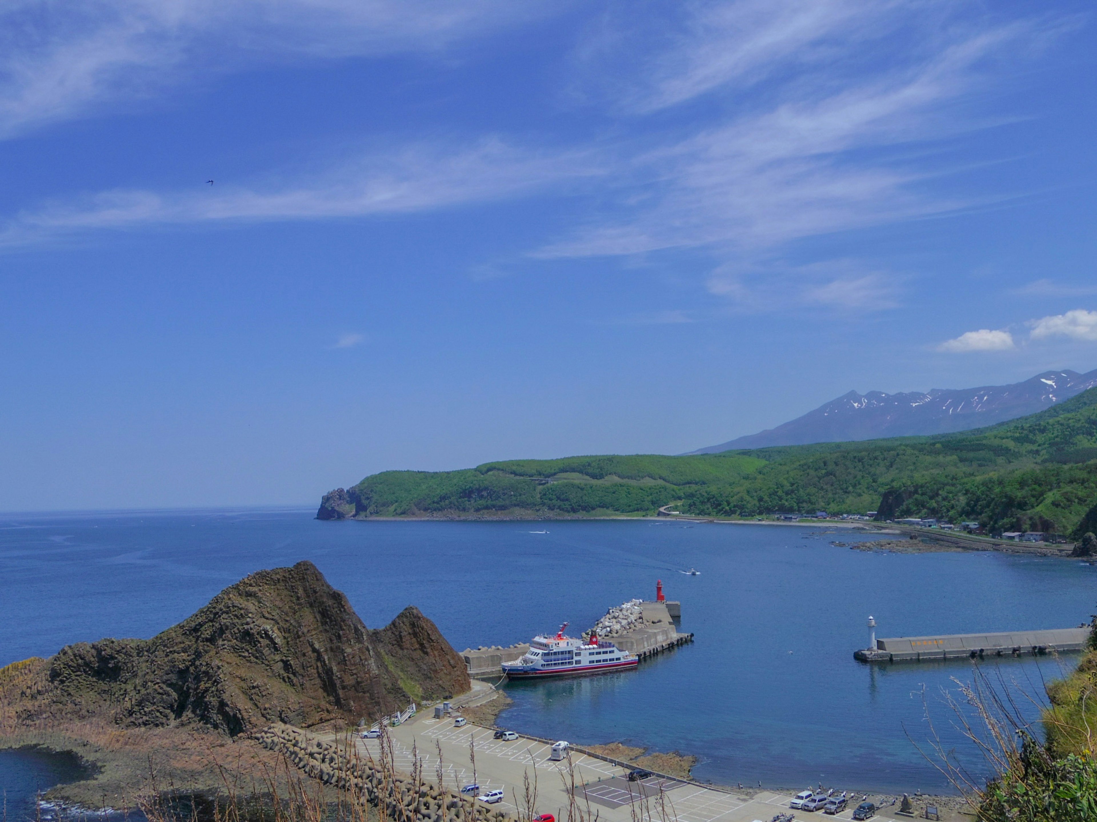 Vista escénica del mar azul y montañas verdes con barcos atracados