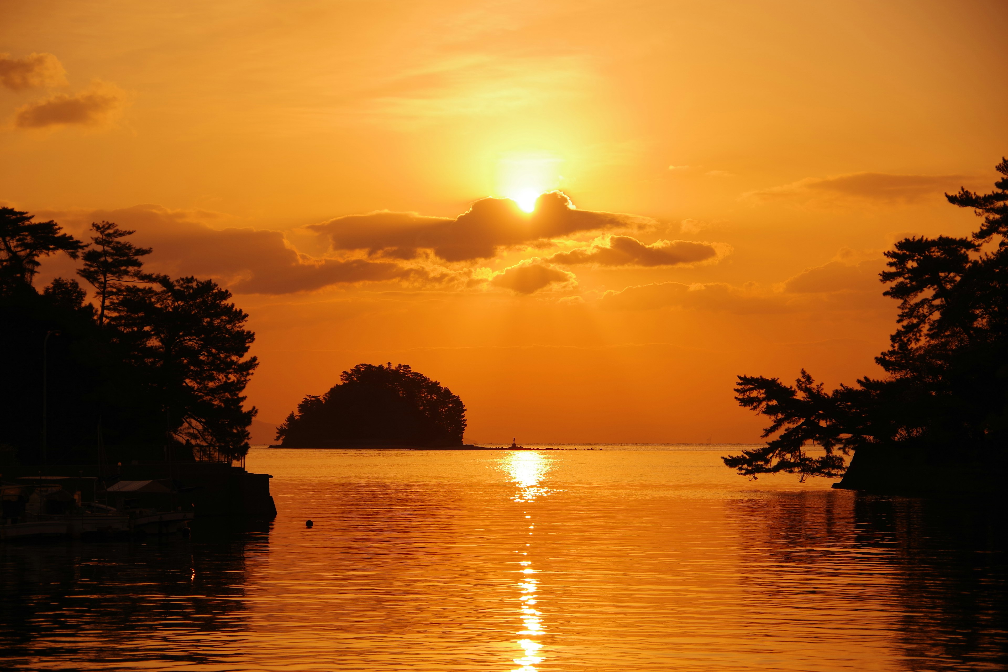 Schöner Sonnenuntergang über dem Meer mit Silhouette einer Insel und Bäumen