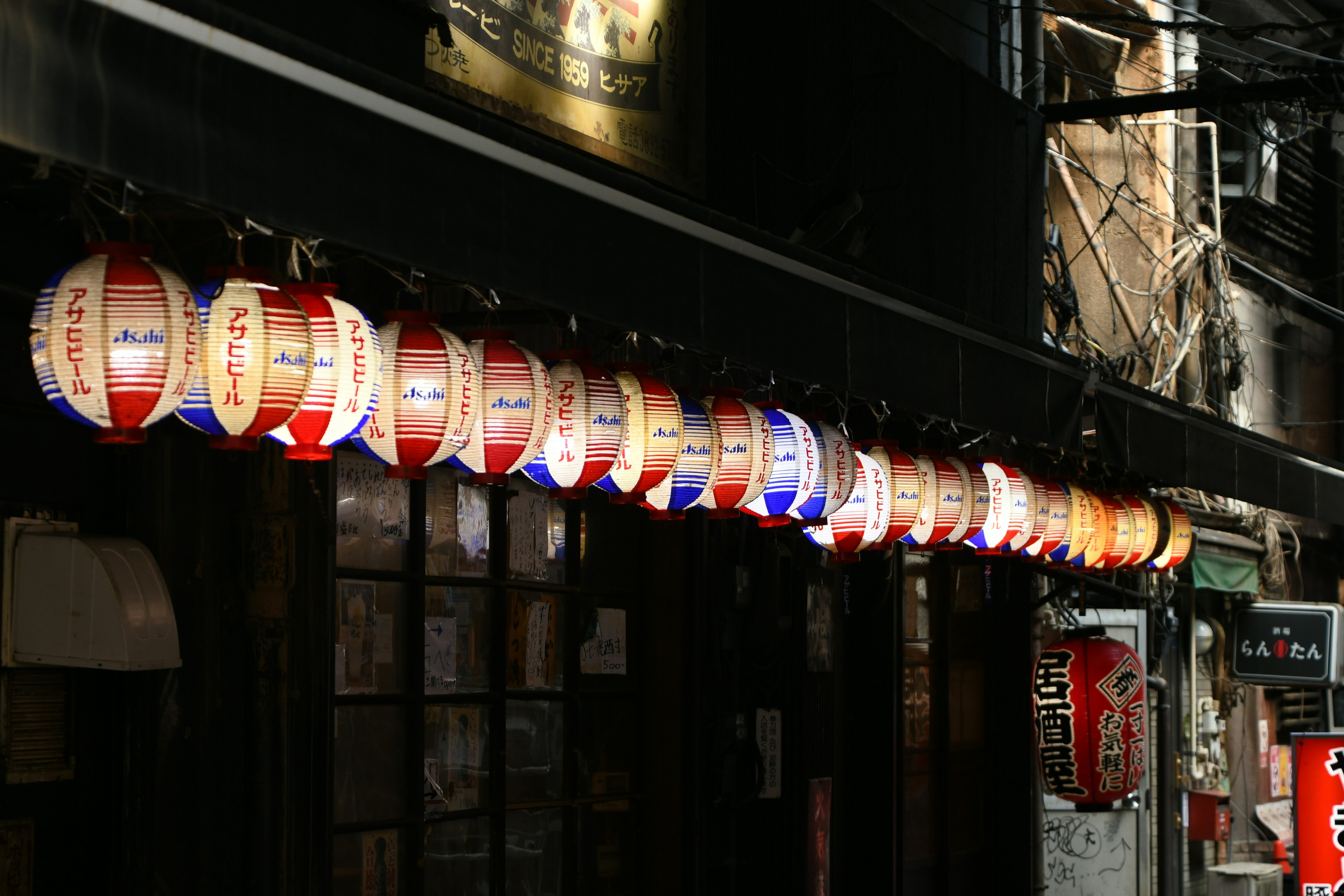 Colorful lanterns hanging in a dark street with restaurant signs