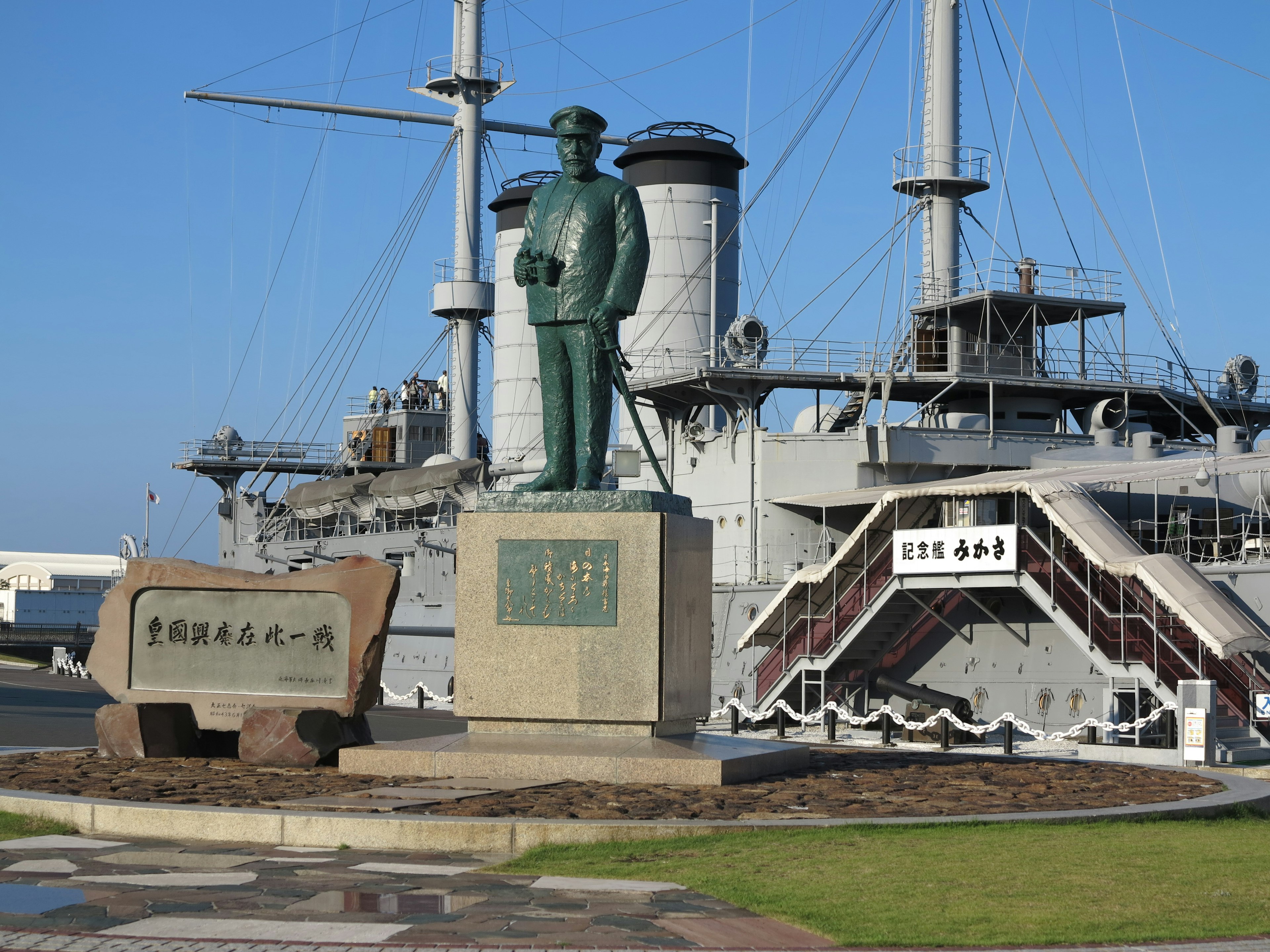 Estatua frente a un acorazado y un monumento