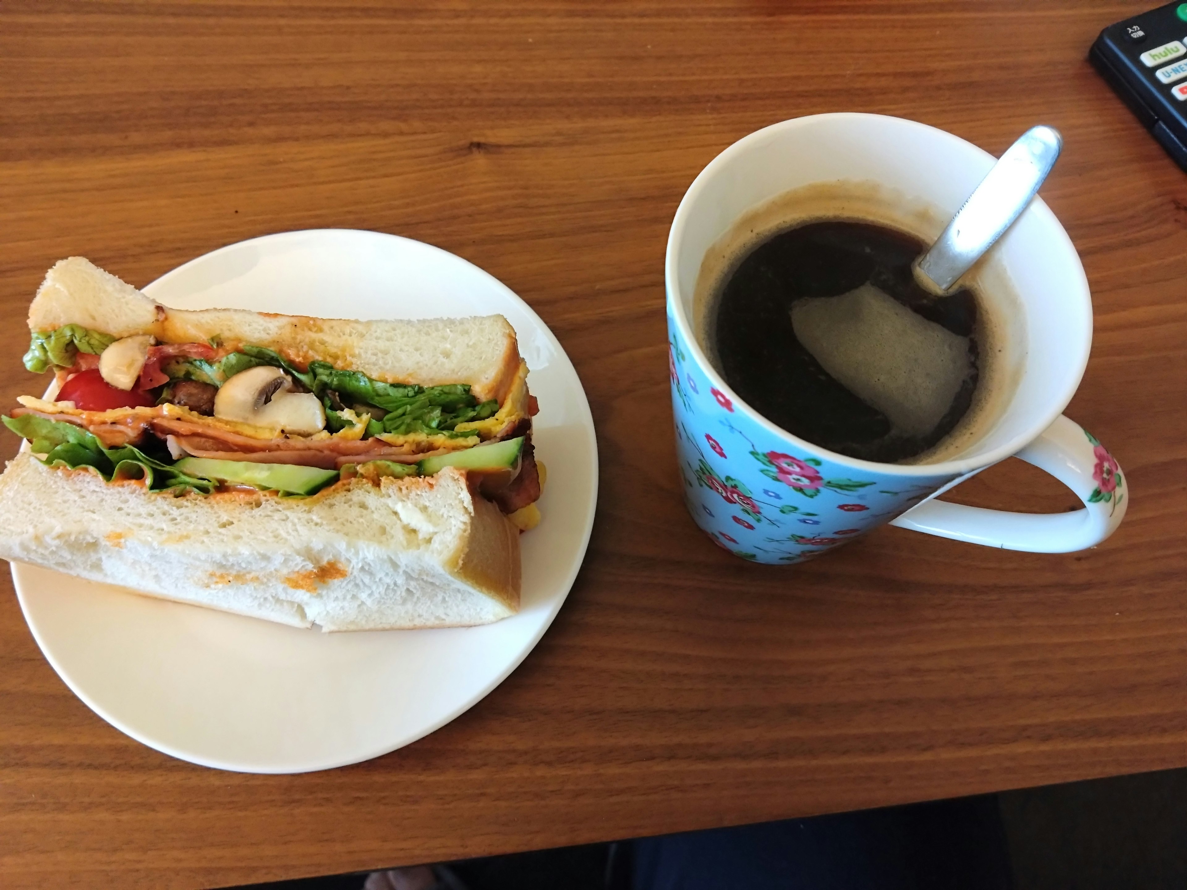 Un sándwich y una taza de café sobre una mesa de madera