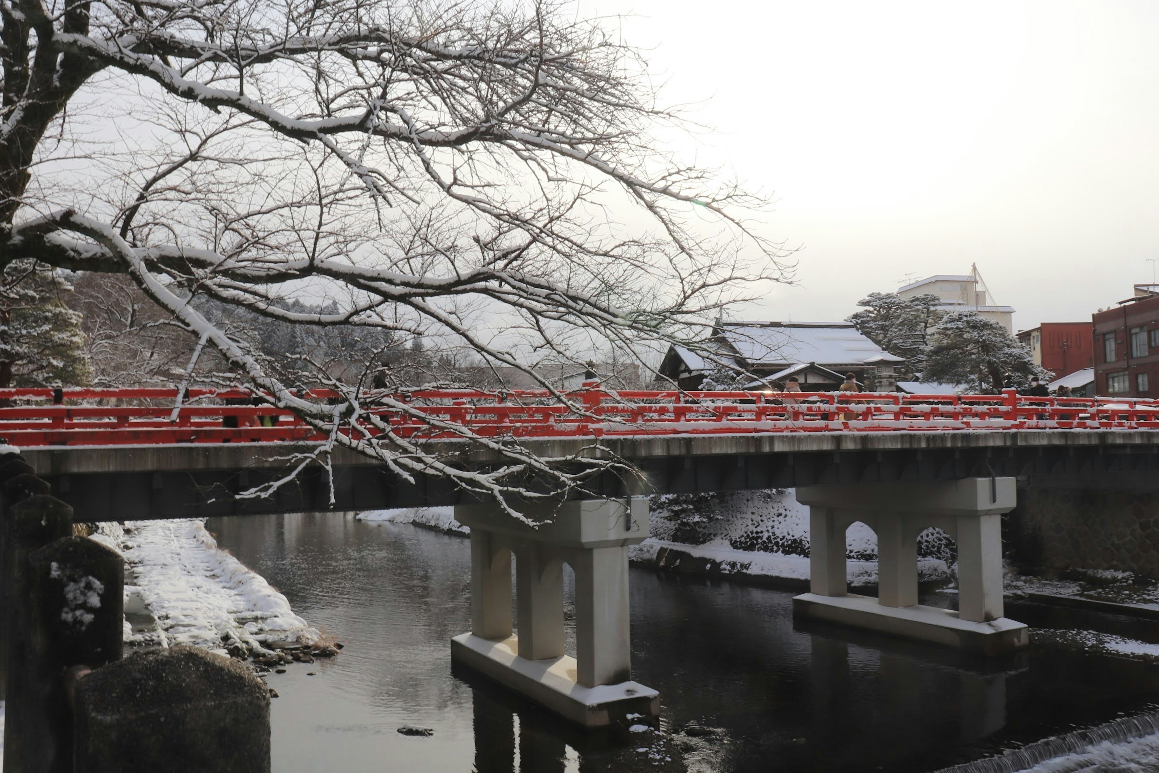 雪覆蓋的紅色橋樑橫跨寧靜的河流