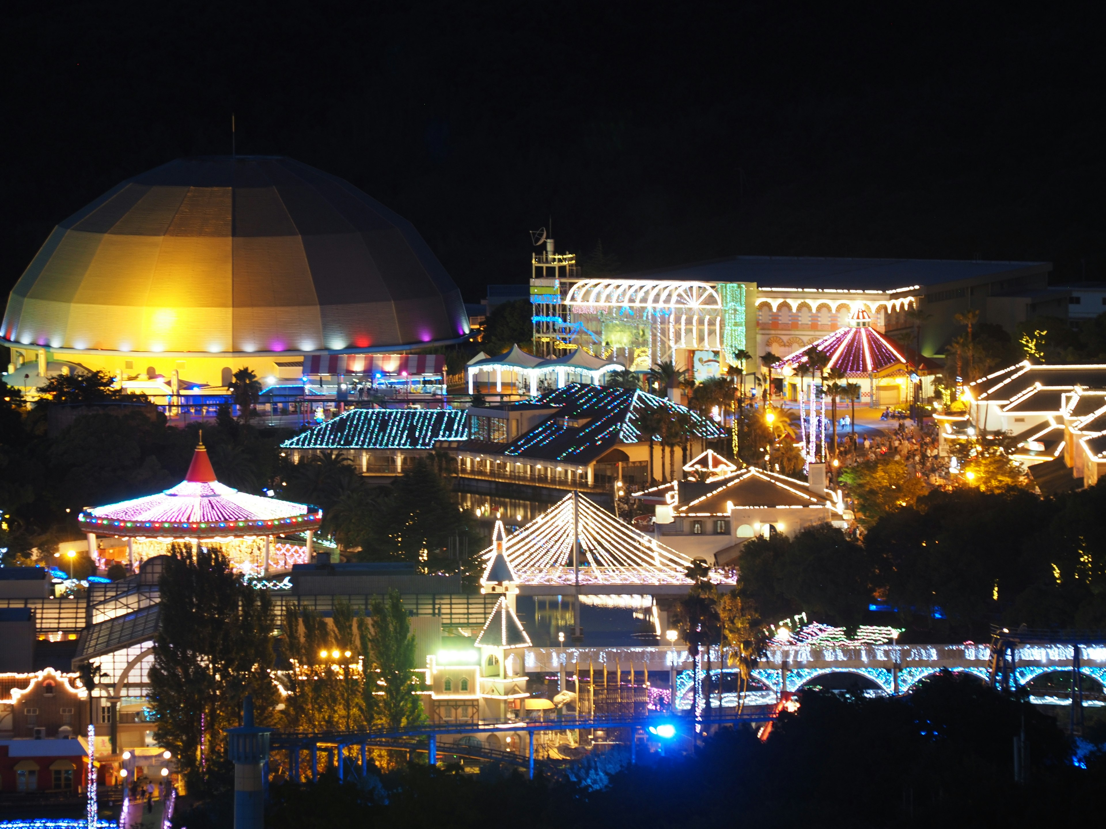 Une scène nocturne vibrante d'un parc d'attractions avec des lumières colorées