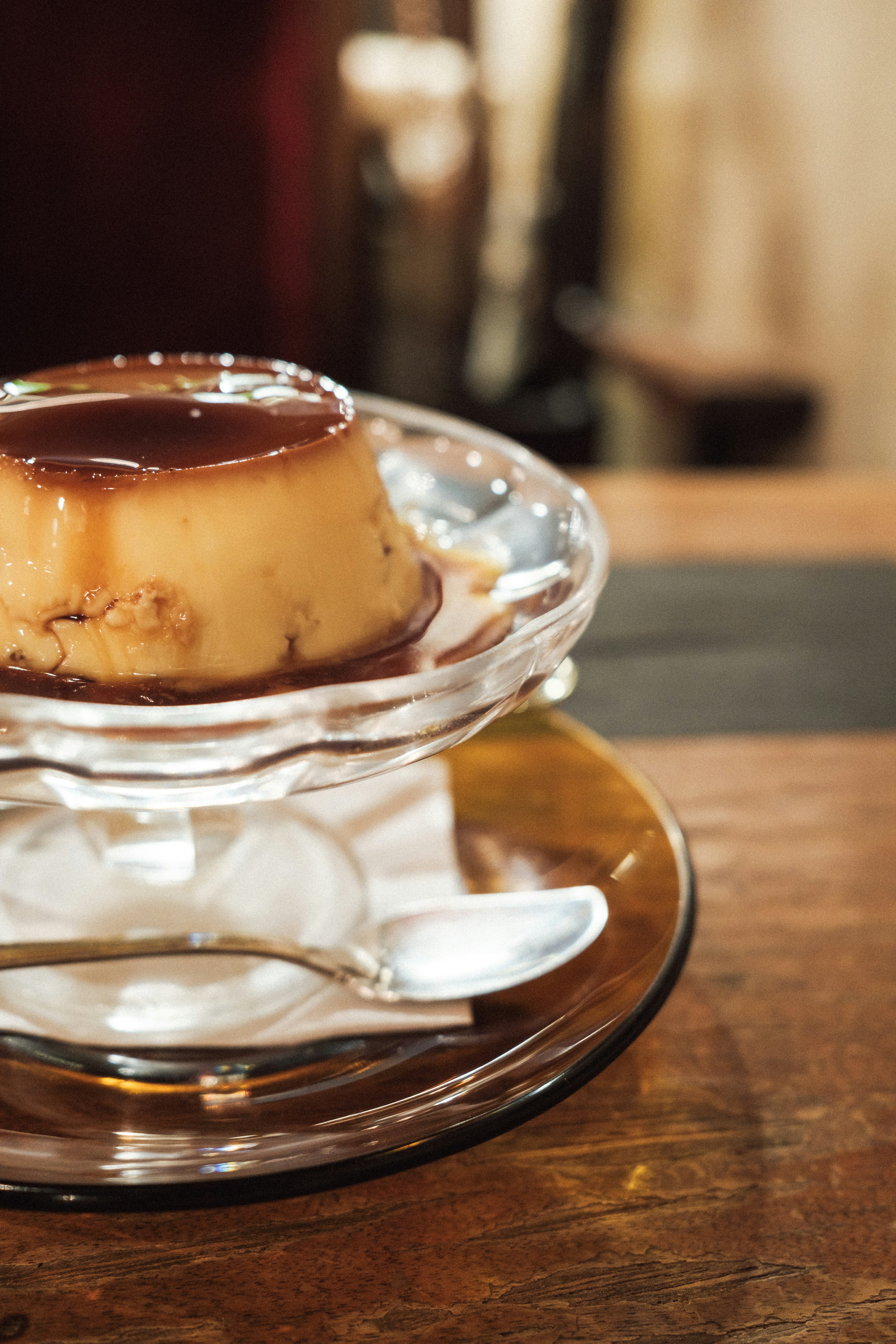 Pudín de crema servido en un plato transparente con salsa marrón