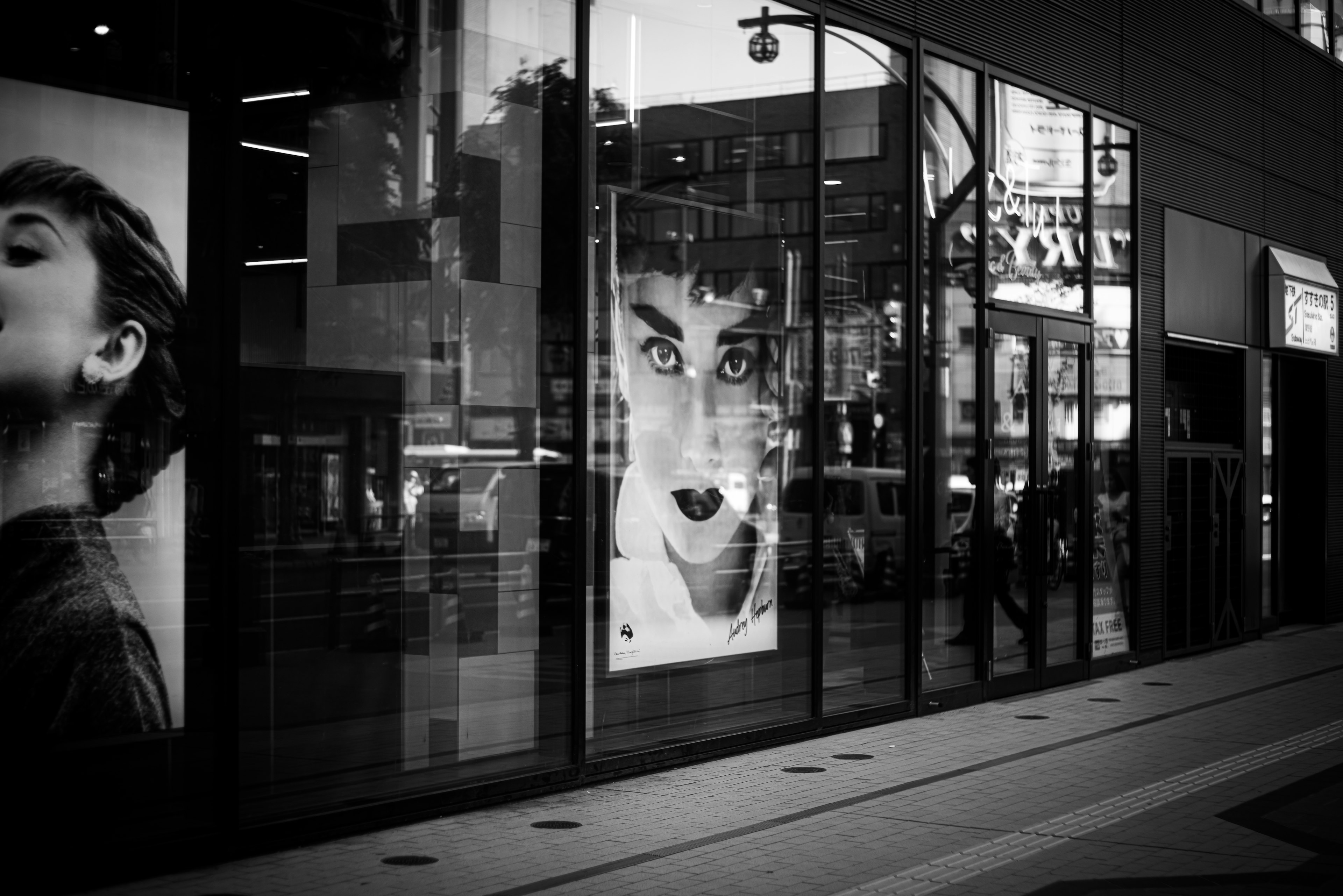 Escena de calle en blanco y negro con un cartel de una actriz famosa