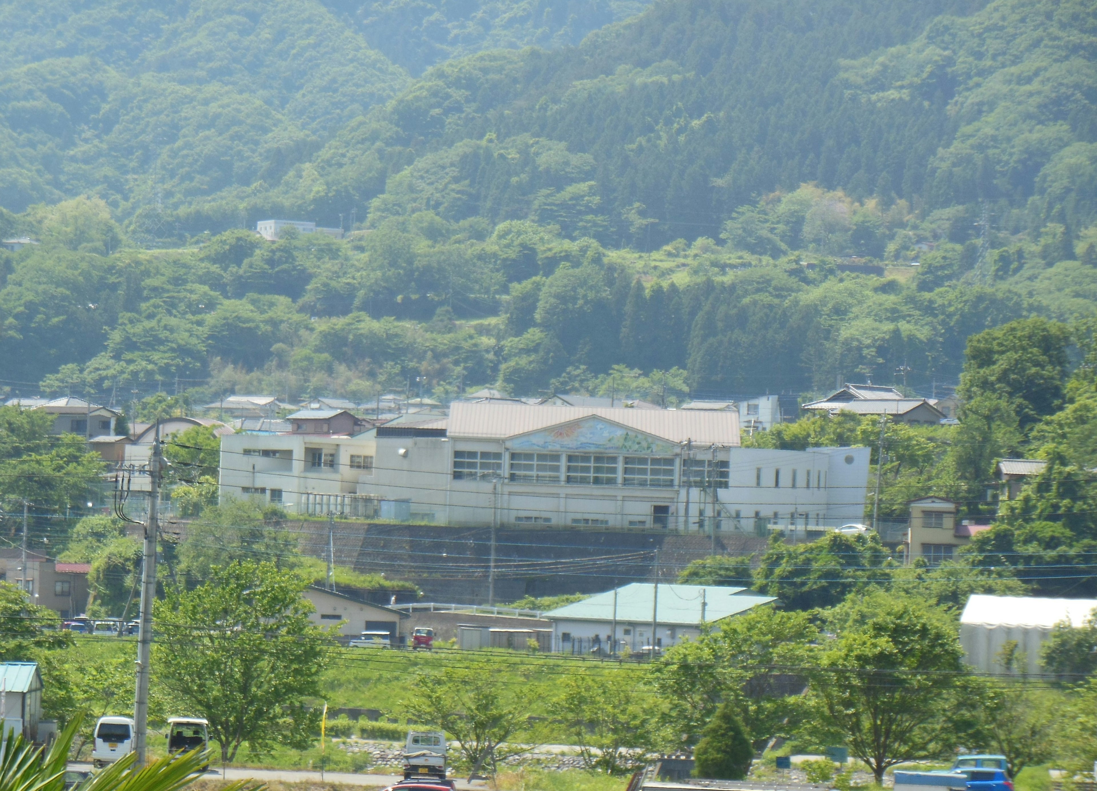 A white building surrounded by lush green mountains and nearby settlements