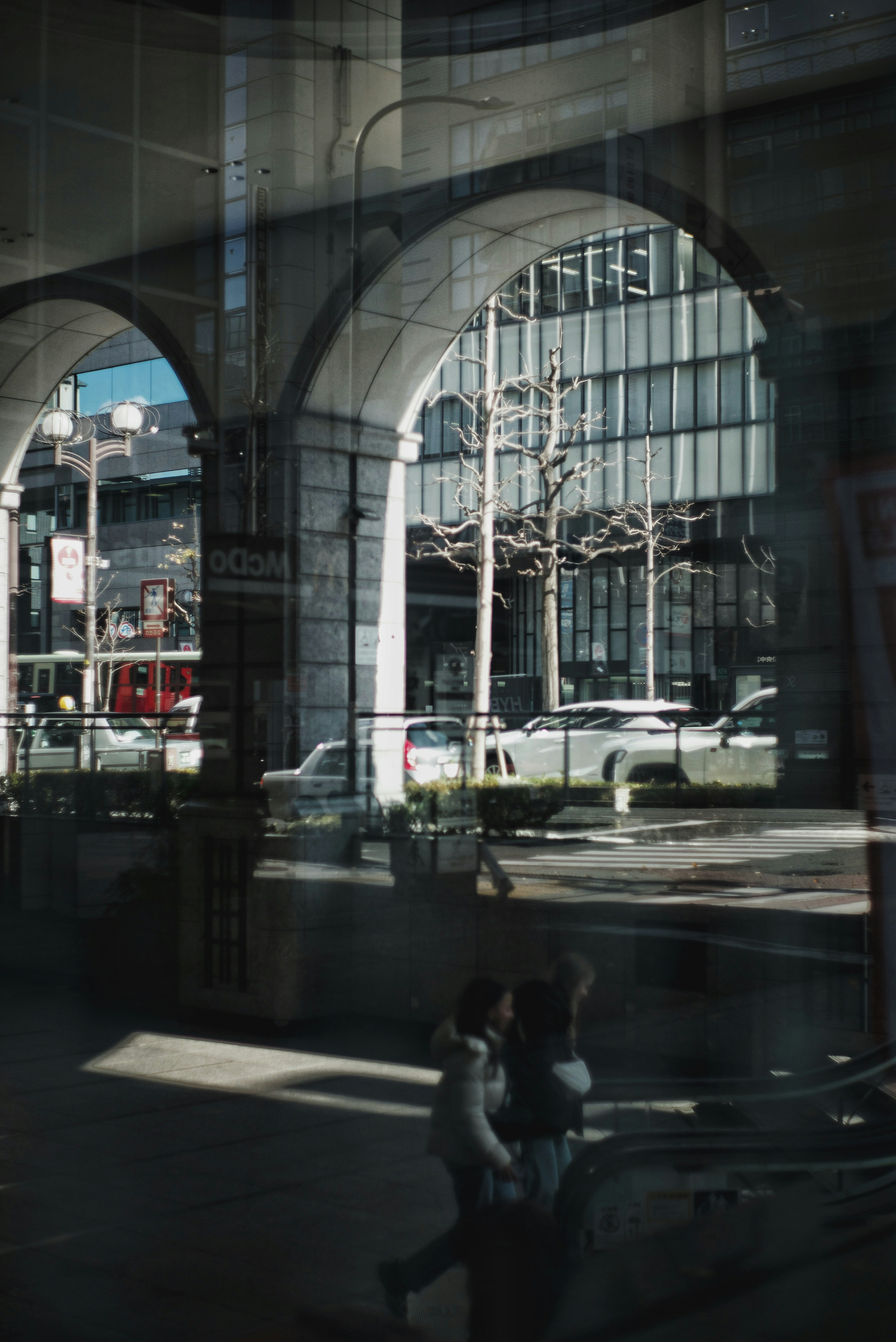 Vista del paisaje urbano a través de ventanas arqueadas con reflejos de personas