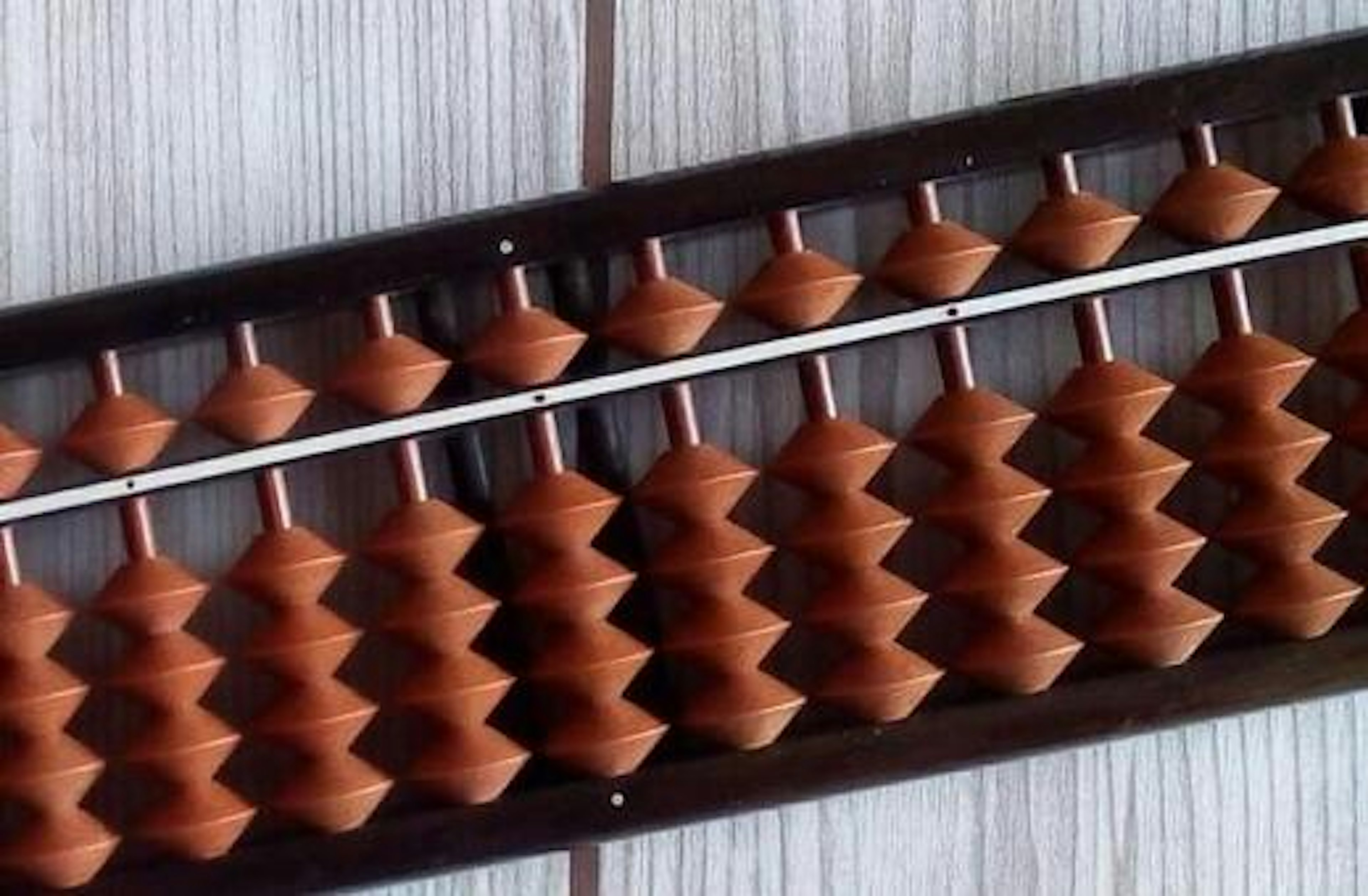 Close-up of a wooden abacus featuring smooth grains and reddish-brown beads