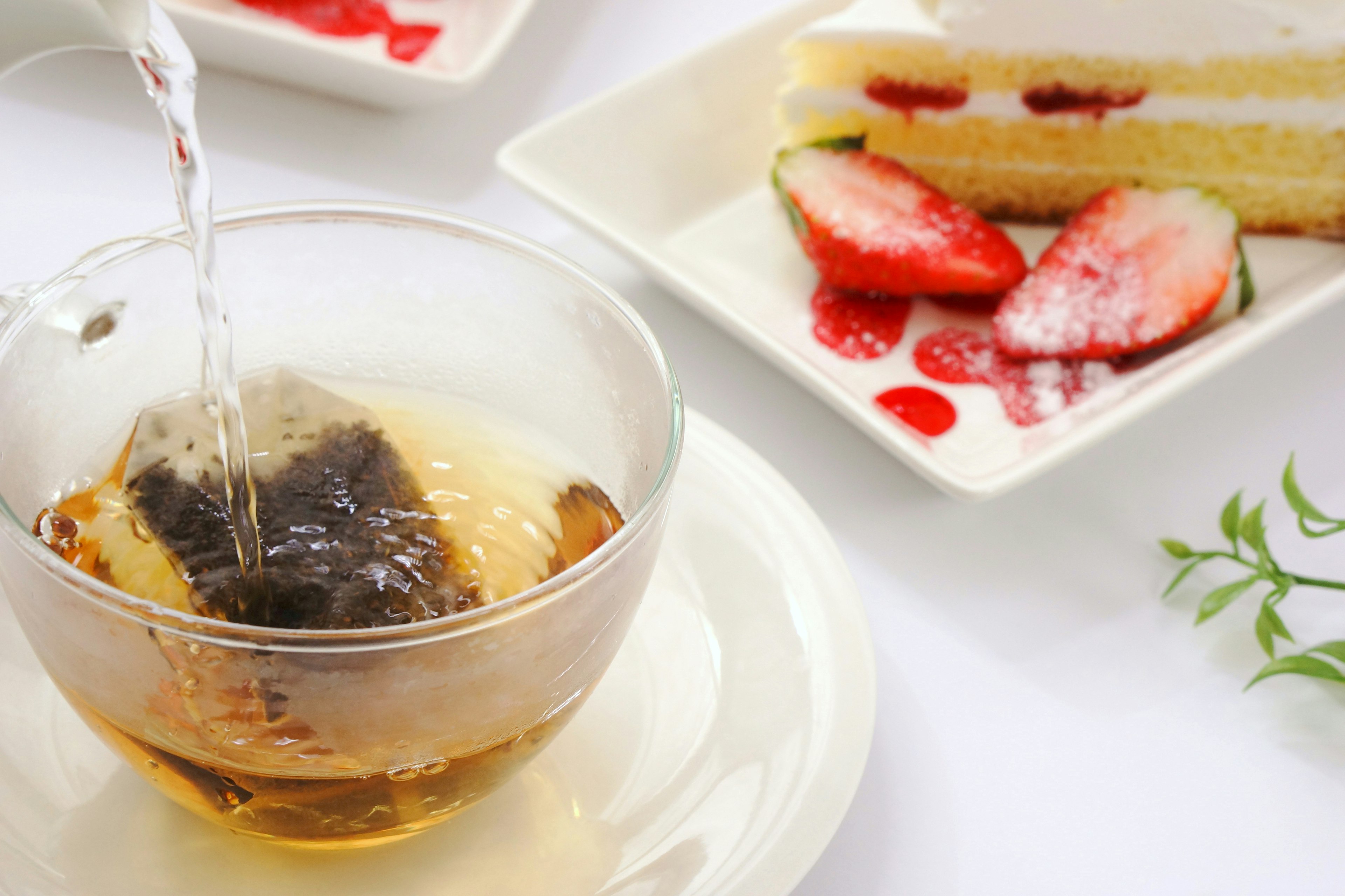 Tasse transparente avec du thé versé et gâteau aux fraises