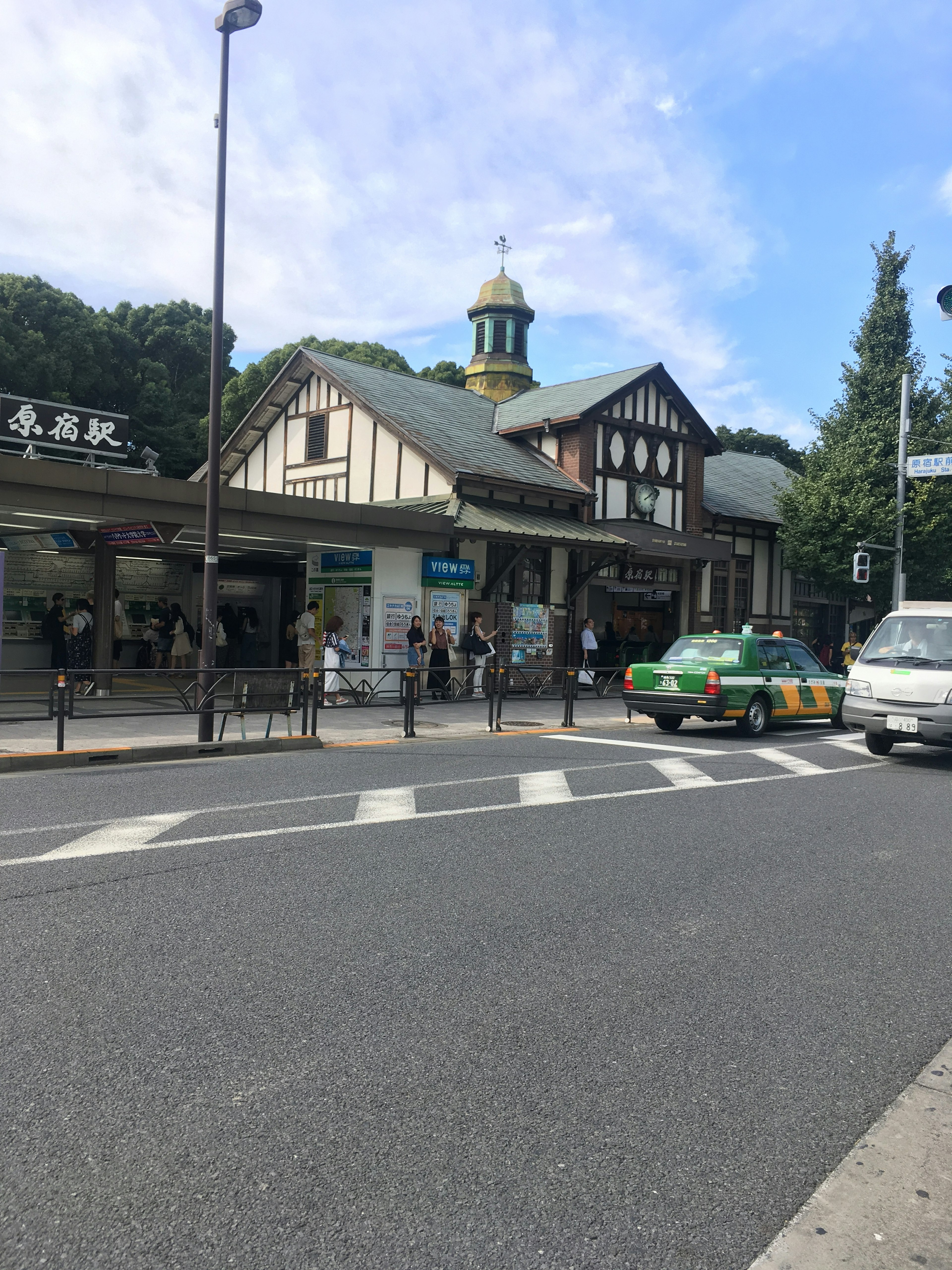 View of a train station with a green taxi and people