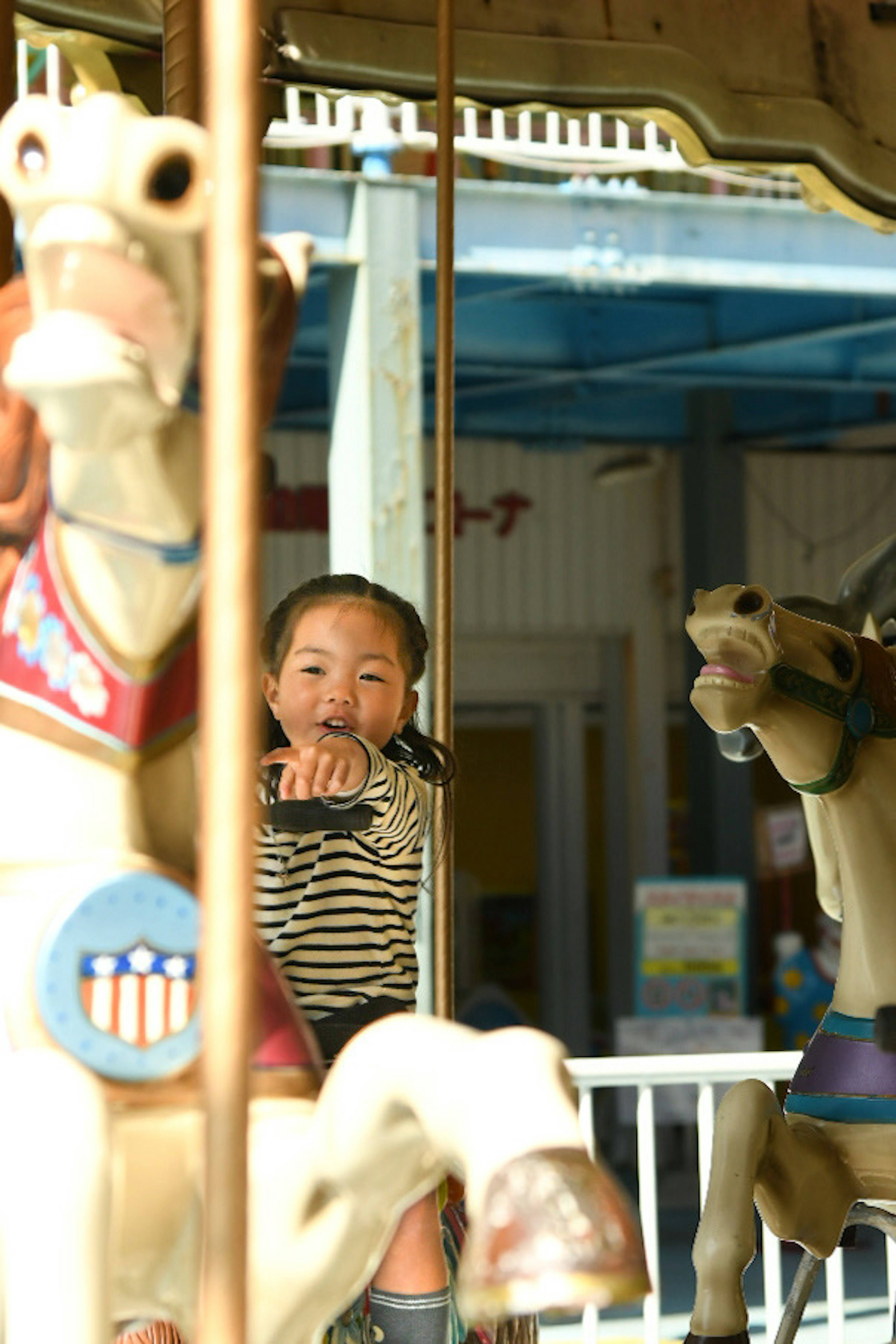 Niña en un carrusel con esculturas de caballos en un parque de atracciones