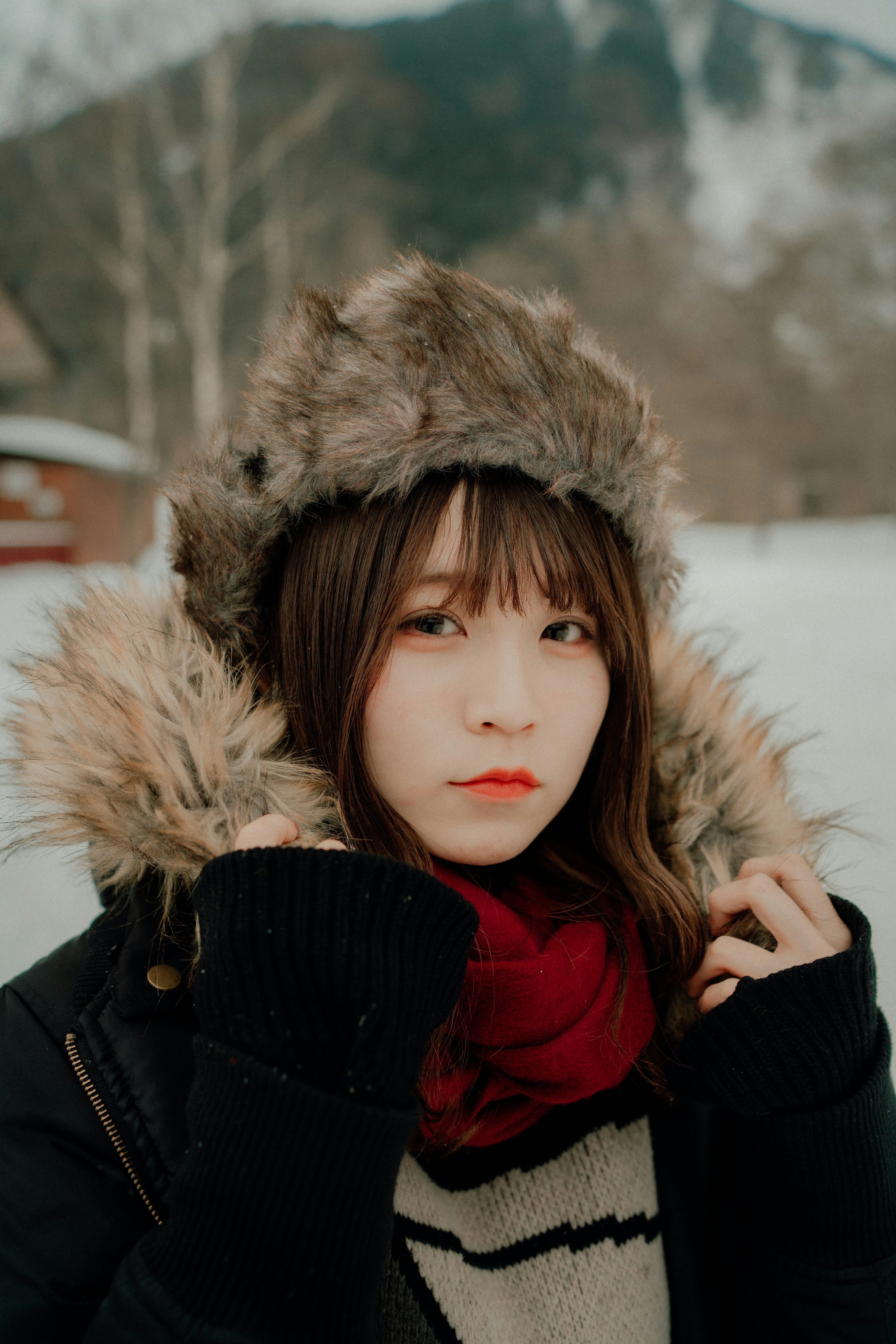 雪景色の中でファー付きの帽子をかぶった女性のポートレート