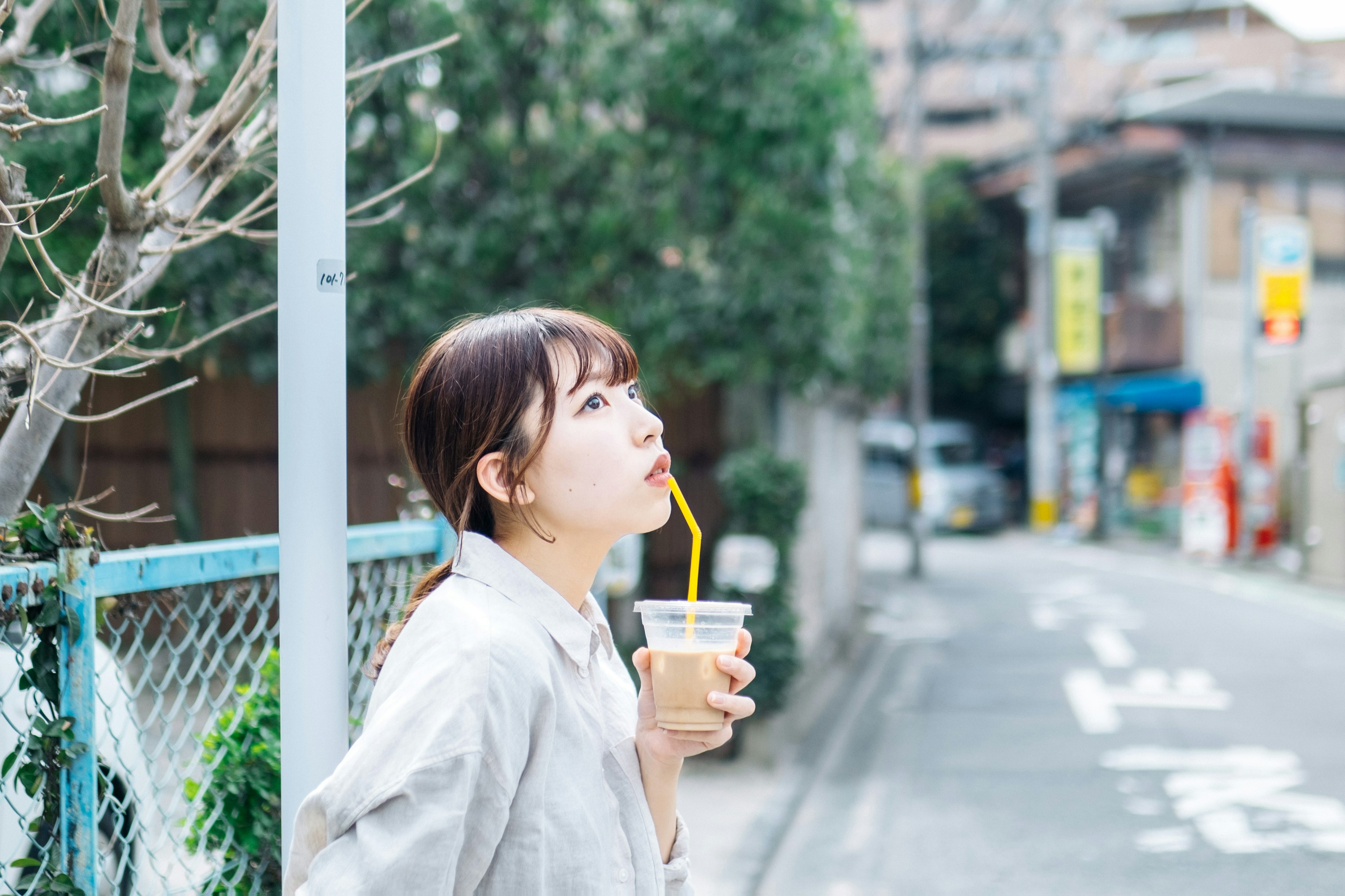 Mujer bebiendo una bebida con una pajita en un entorno de calle tranquila