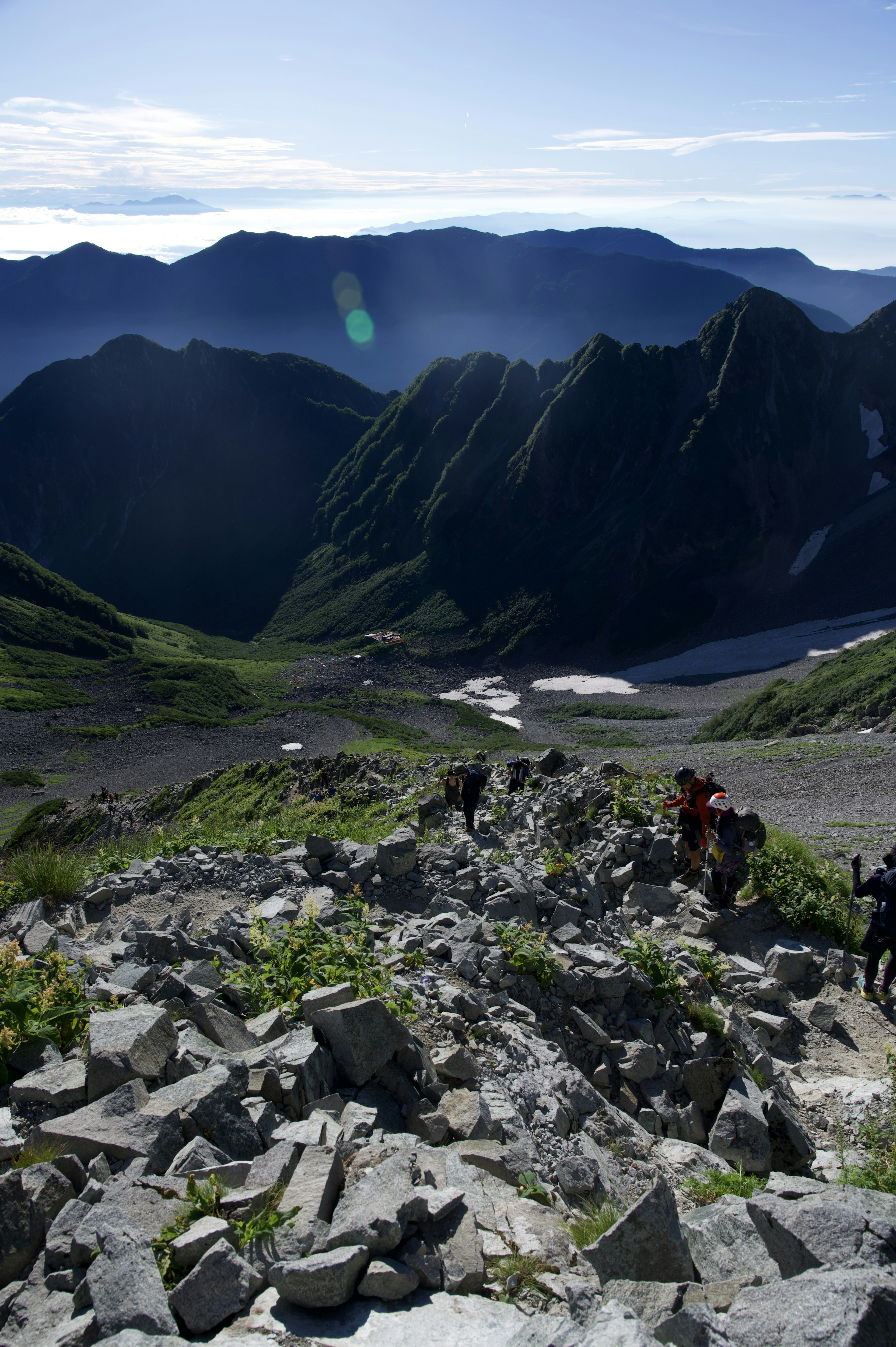 高山の風景と登山者が見える岩だらけの道