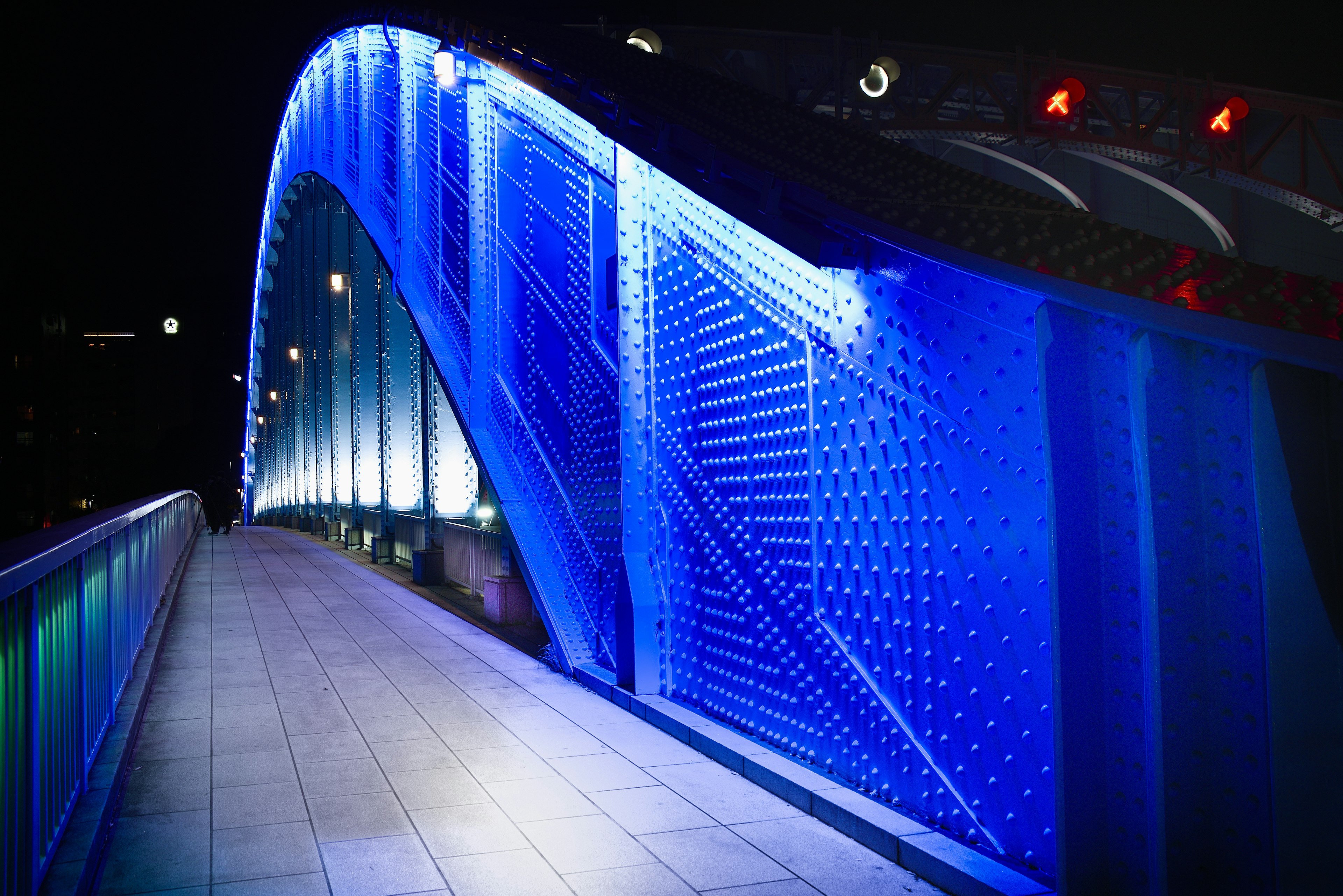 Seitenansicht einer Bogenbrücke, die nachts in blauem Licht beleuchtet ist