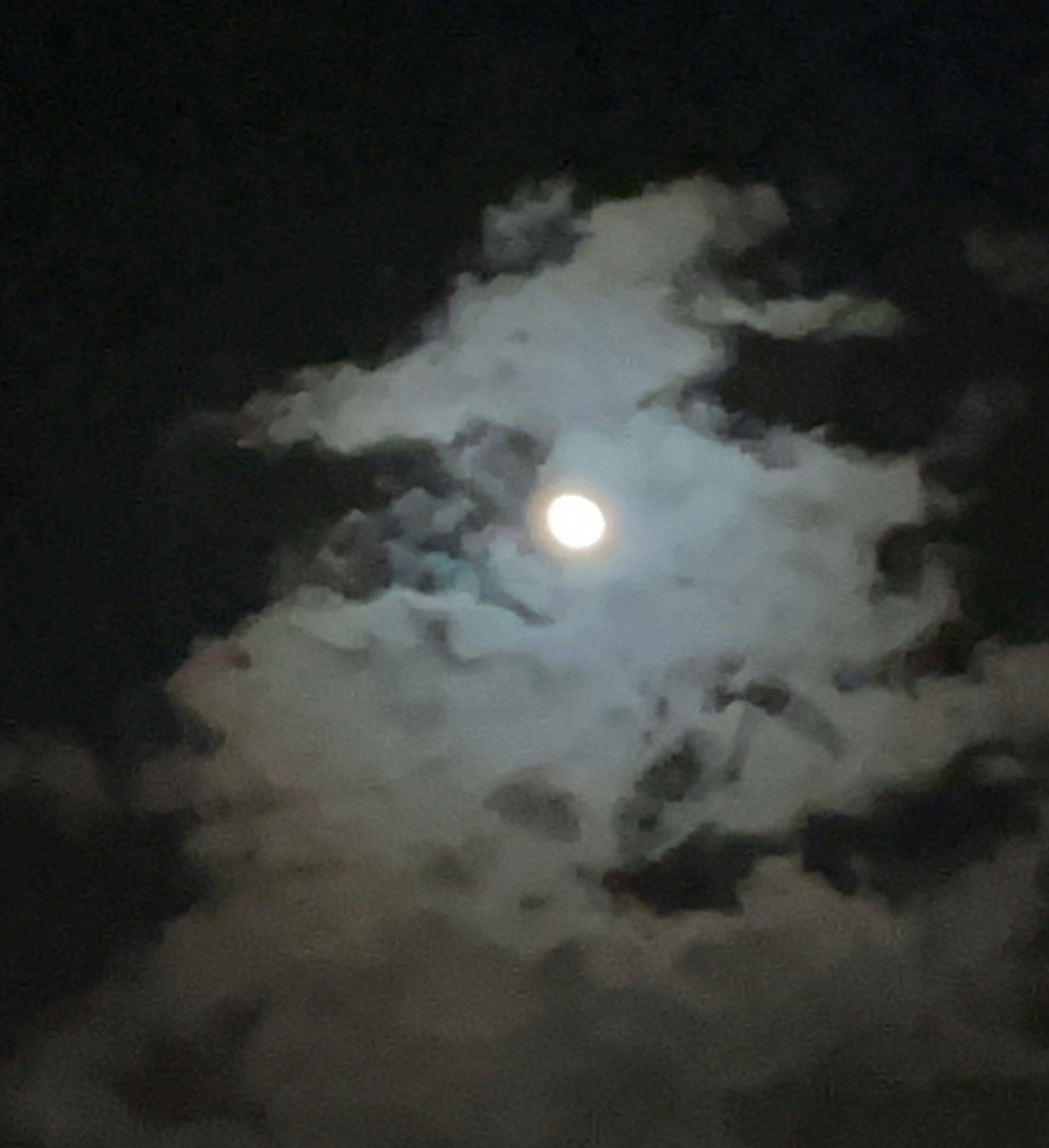 Bright moon surrounded by clouds in a dark night sky